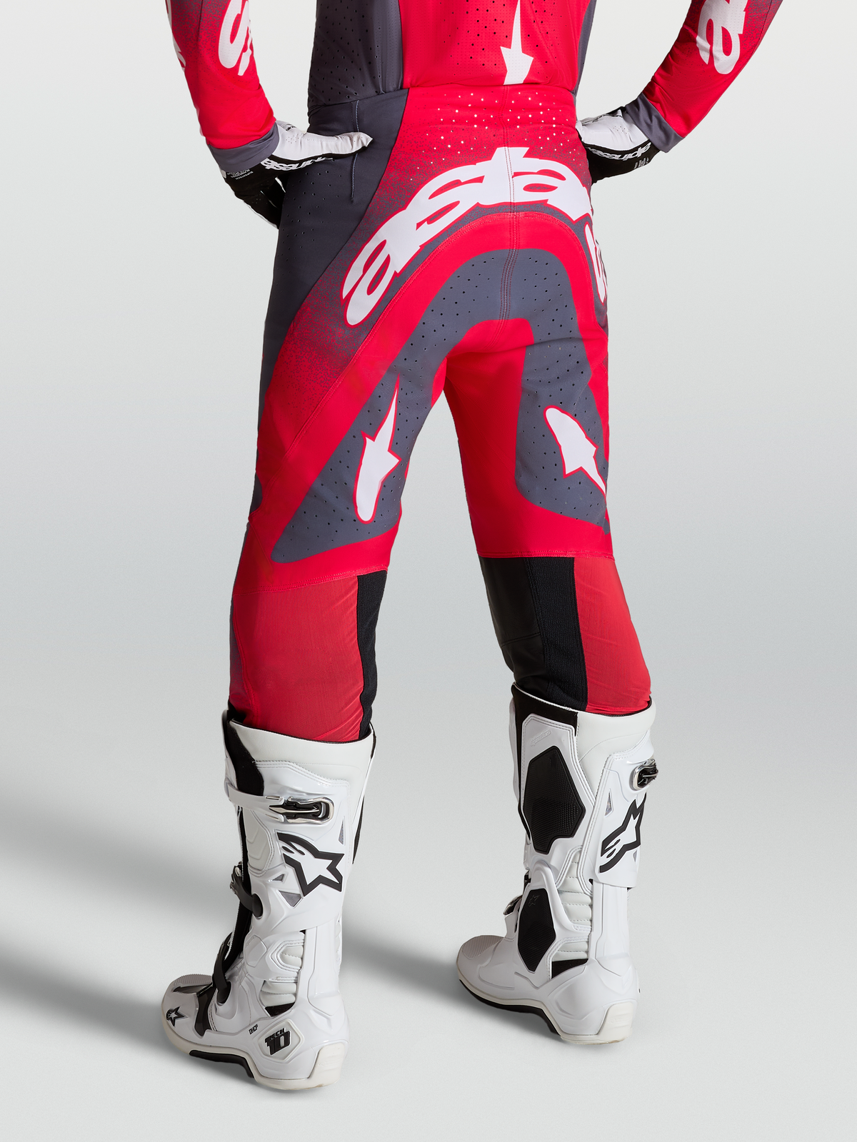 Alpinestars Supertech Hiten AFD broek, rood en grijs, motocross-racebroek op model, zijaanzicht met witte race-laarzen.