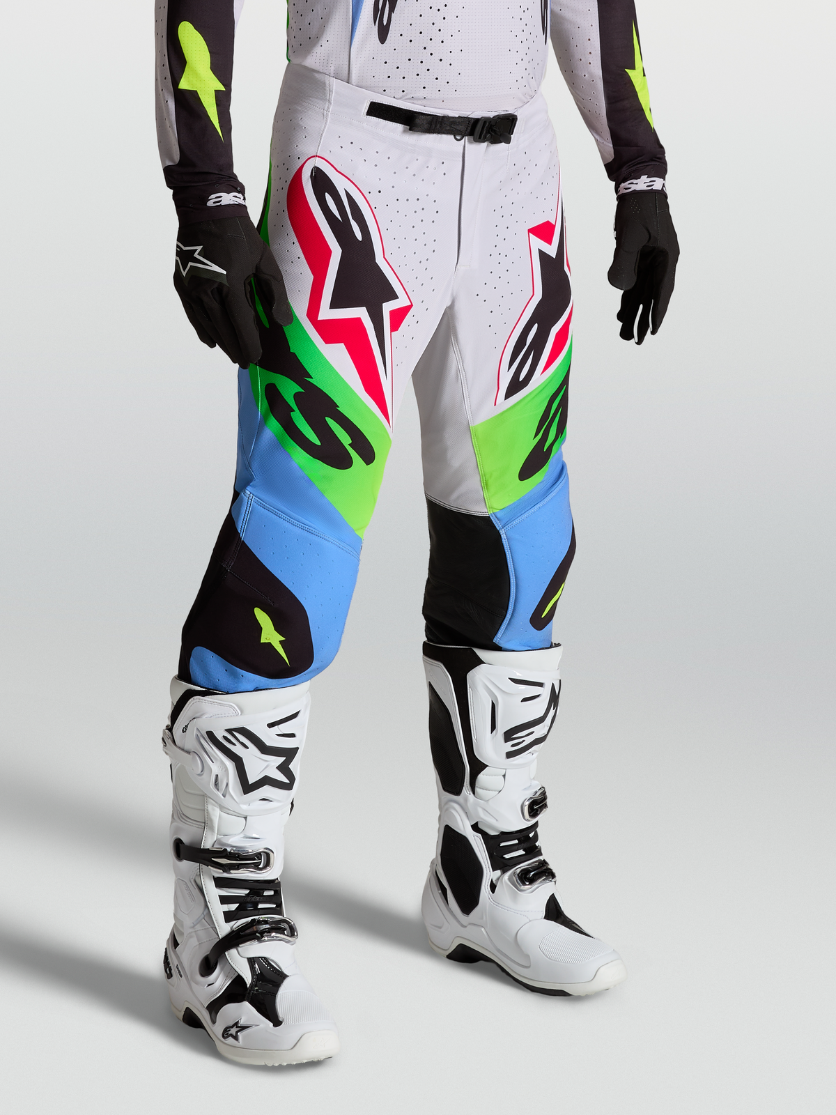 Pantalon Alpinestars Supertech Dyna, pantalon de motocross vert et bleu, porté avec des bottes blanches