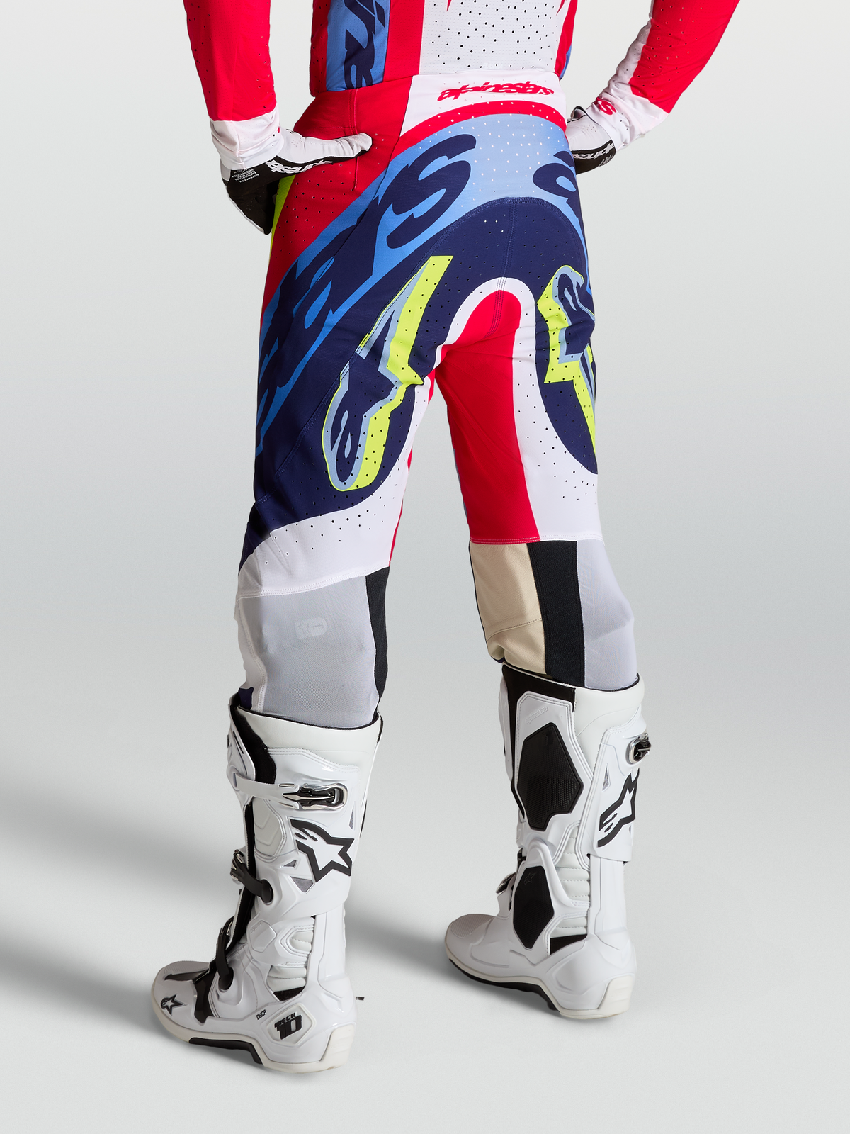 Alpinestars Supertech Dyna Broek, rood, wit en navy blauw, motocross broeken met atletische racepasvorm op model.