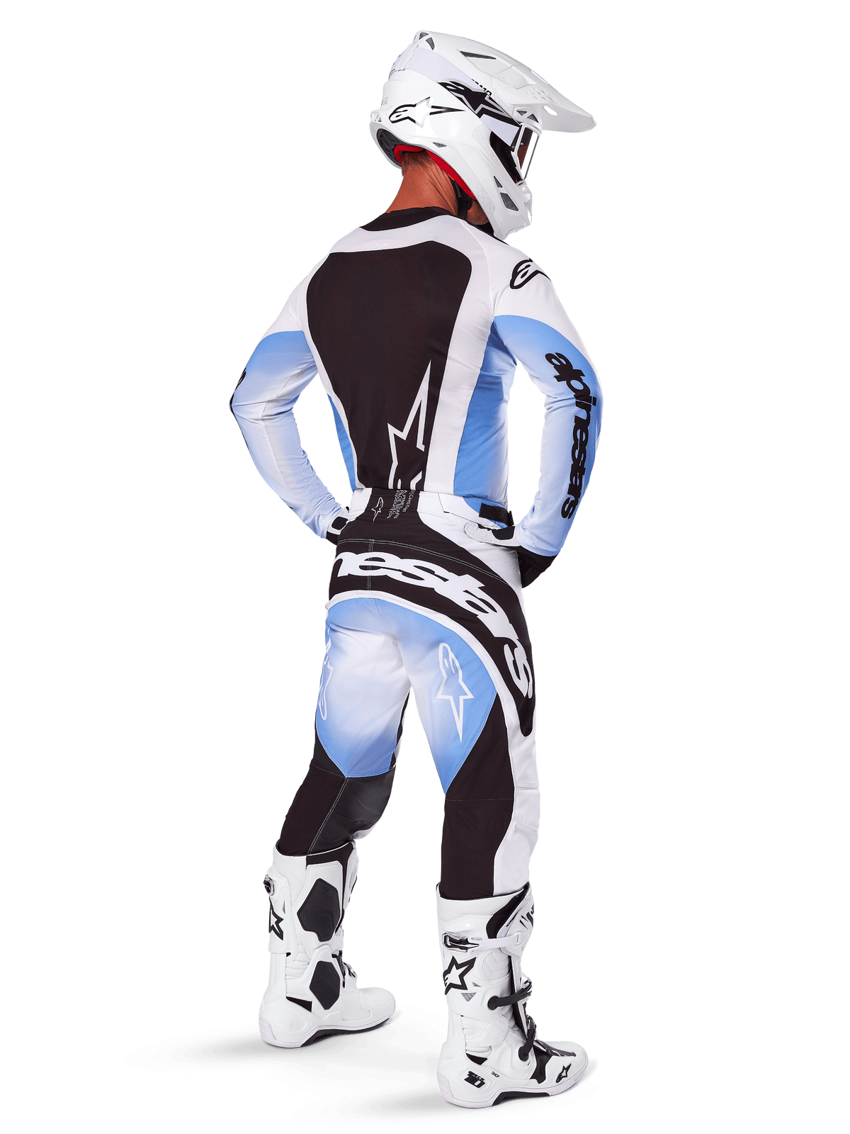 Pilote de motocross vu de dos portant le pantalon et le maillot Alpinestars 2025 Techstar Melt, design dégradé noir, bleu et blanc, casque blanc, bottes blanches et noires, tenue de course tout-terrain complète.