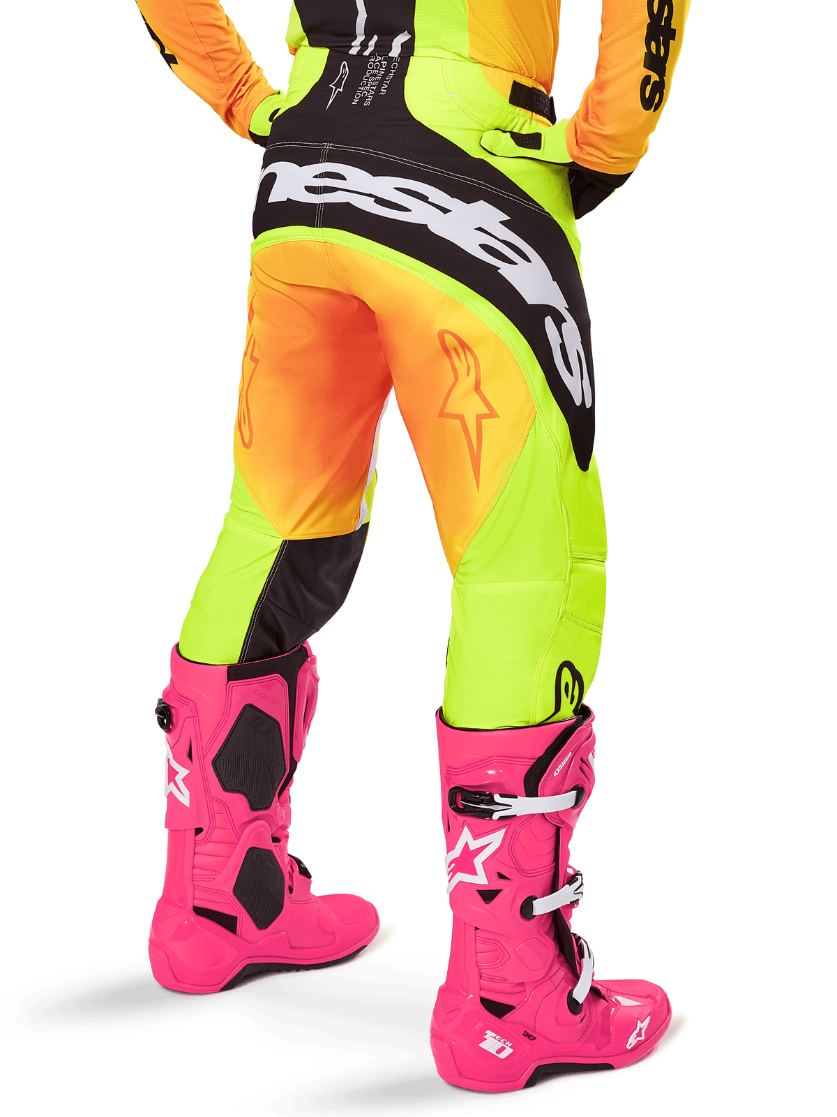 Rückansicht eines Motocross-Fahrers in der Alpinestars 2025 Techstar Melt Hose, gelb-orangefarbener Farbverlauf mit schwarz-weißem Branding am Gesäß, kombiniert mit leuchtend pinken Motocross-Stiefeln, Performance-Offroad-Ausrüstung.