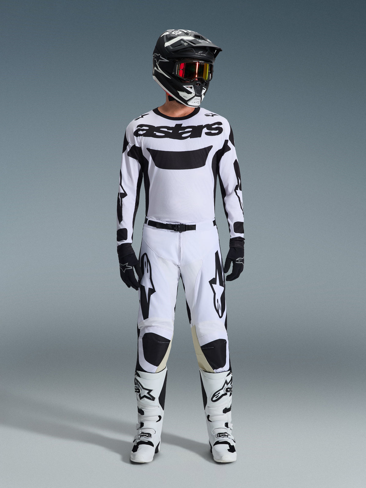 Alpinestars 2026 Racer Riway Broek, motorcrossbroek in wit en zwart, gedragen door een motocrosser met bijpassend wit shirt, zwarte helm met rode bril, zwarte handschoenen en witte laarzen, voorzien van opvallende zwarte Astars-branding, prestatiegericht ontwerp voor off-road gebruik