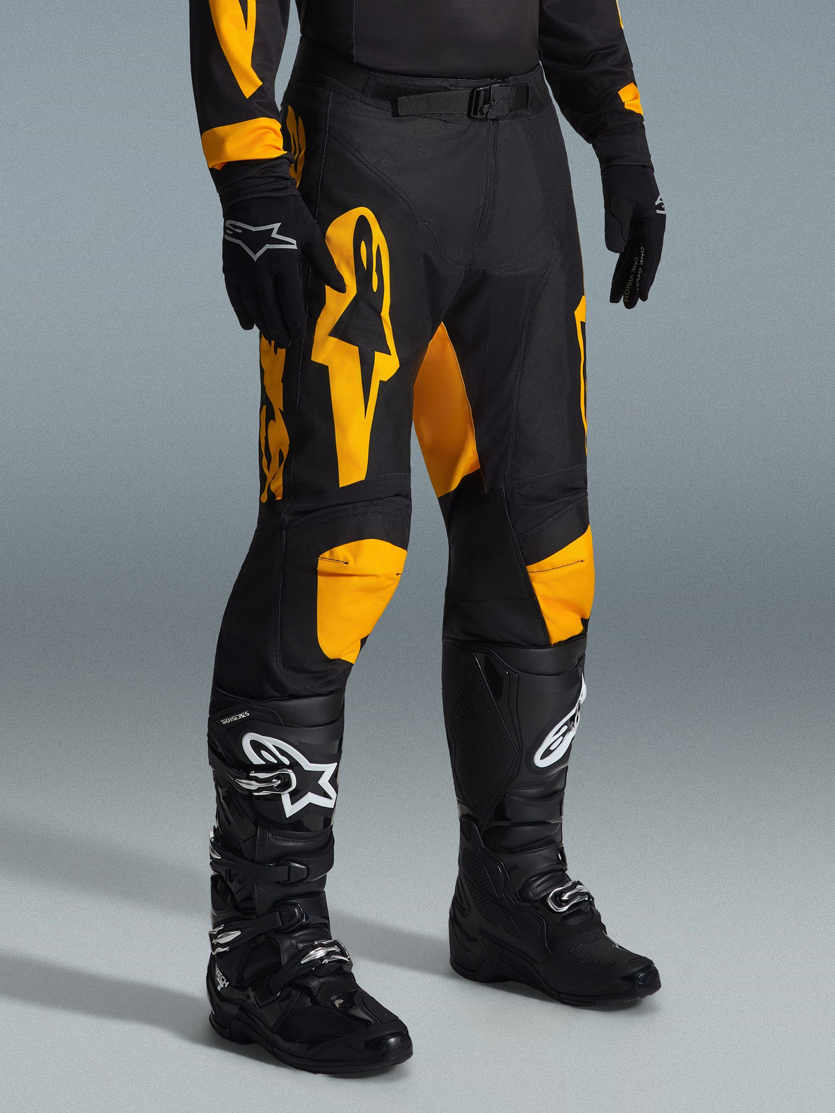 Alpinestars 2026 Racer Riway Pants, pantalon de motocross, jaune et noir, porté avec des gants et des bottes de motocross noirs, arborant un marquage Alpinestars jaune vif et des accents aux genoux sur un châssis noir, conçu pour la performance tout-terrain