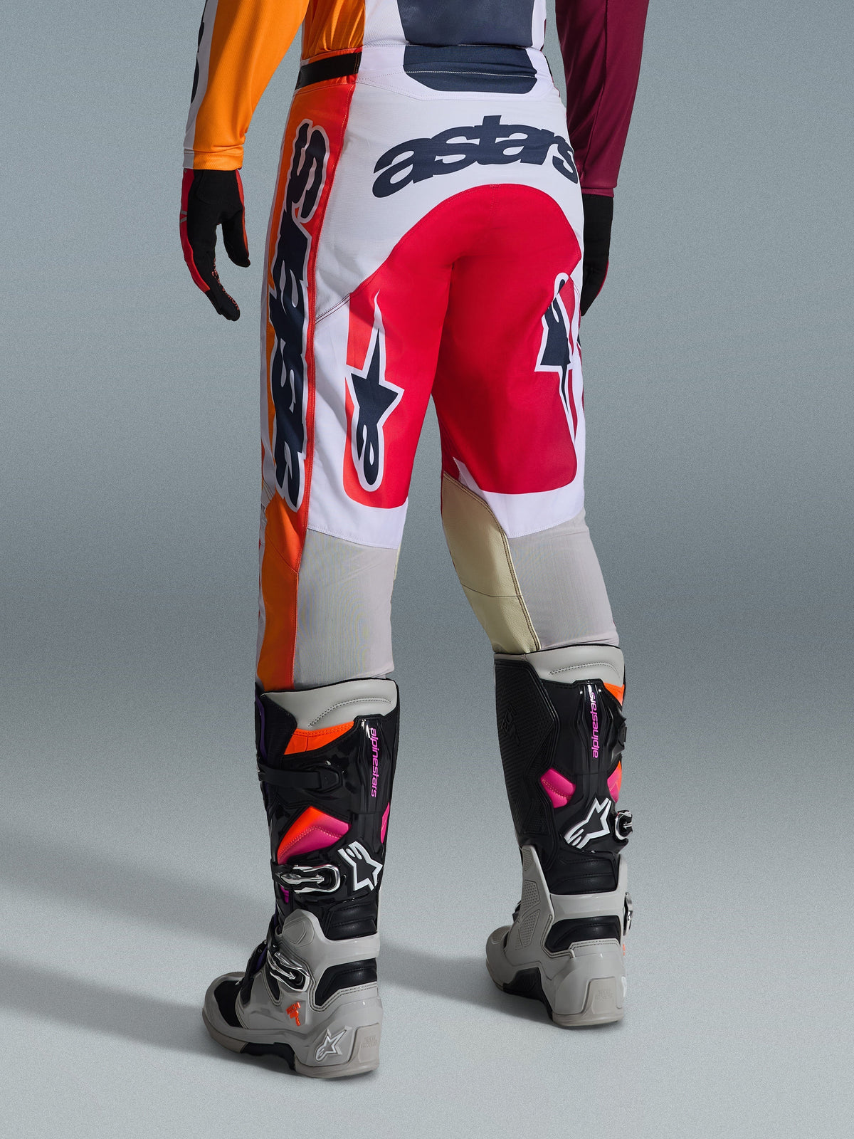 Alpinestars 2026 Racer Portl Pants, pantalon de motocross, rouge, gris clair et gris foncé, vue arrière présentant un marquage audacieux et les détails du logo, associé à des bottes et des gants de motocross coordonnés, équipement de performance pour la course tout-terrain.
