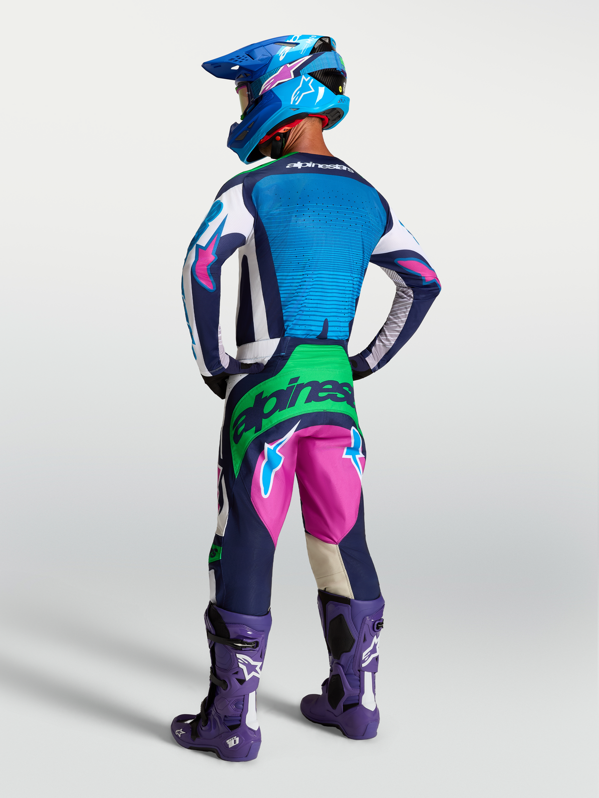 Alpinestars Techstar Maven, ensemble de motocross bleu et rose, accents vert fluo, vue arrière sur mannequin.