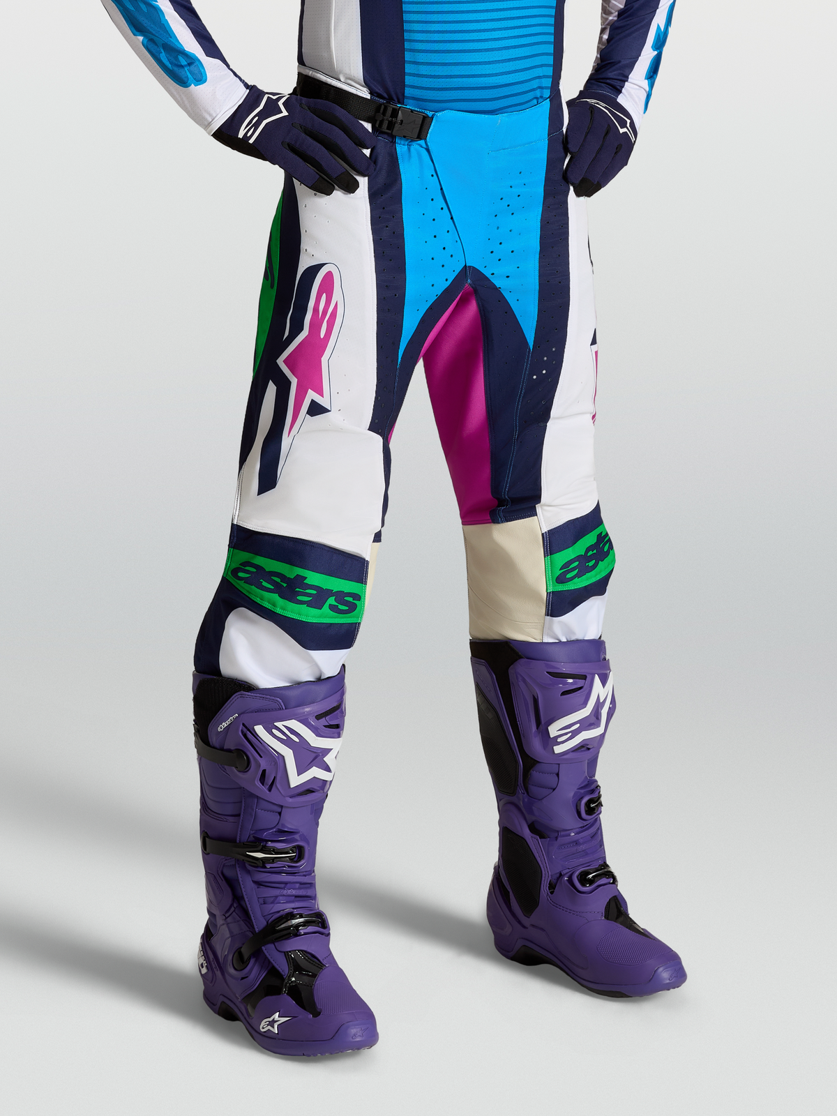 Alpinestars Pantalon Techstar Maven, pantalon de motocross bleu et blanc, porté par un mannequin, doté d'une boucle magnétique et de panneaux extensibles durables.