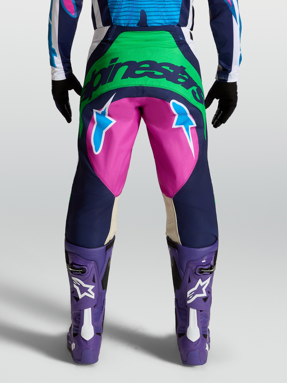 Pantalon Techstar Maven Alpinestars, pantalon de motocross bleu et rose sur mannequin, vue arrière montrant le logo Alpinestars et des graphismes d'étoiles.