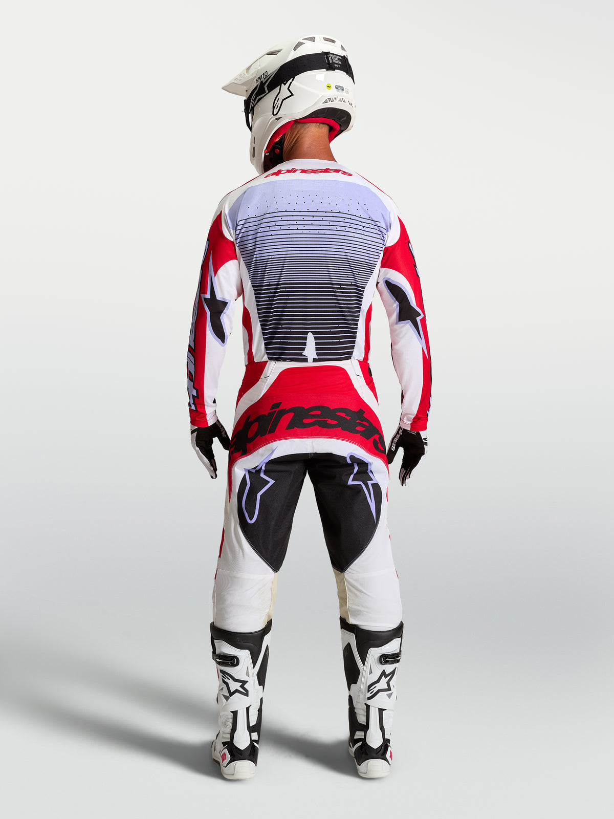 Alpinestars Pantalon Techstar Maven, pantalon de motocross rouge et blanc, vue de dos sur un pilote montrant une coupe athlétique de course.
