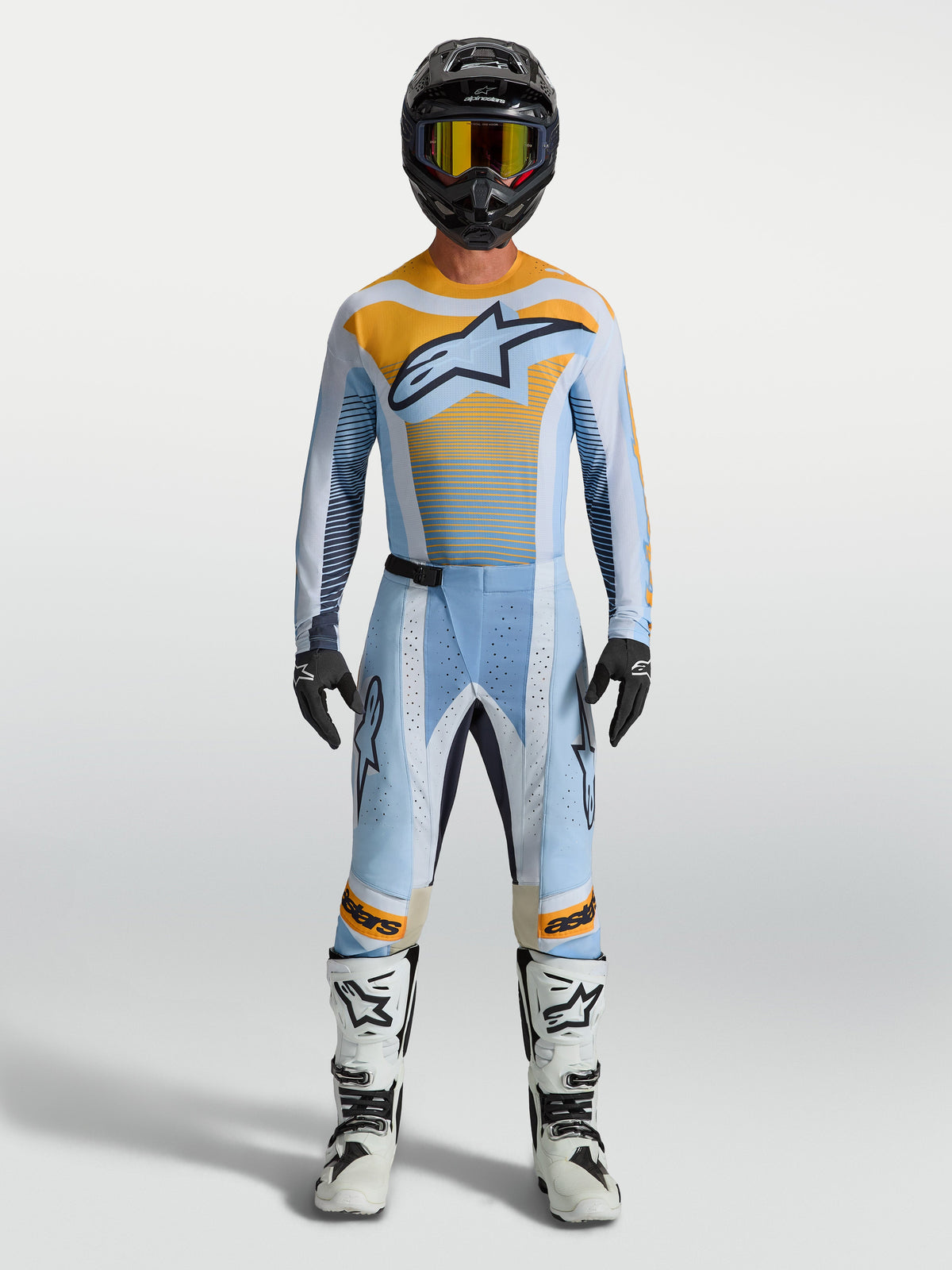 Pantalon Alpinestars Techstar Maven, motocross pour homme, bleu et orange, porté par un pilote, coupe de course, zones extensibles.