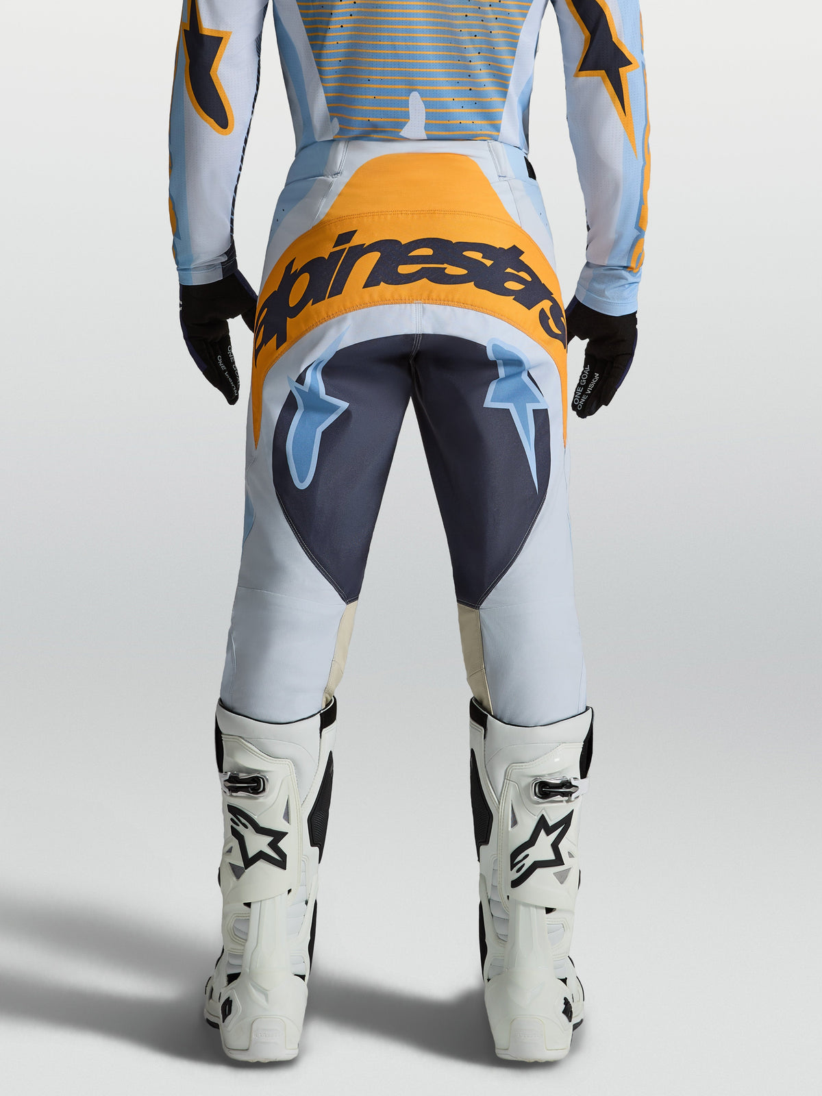 Pantalon Alpinestars Techstar Maven, pantalon motocross homme, bleu et orange, poly-tissu 600D, vue arrière sur un pilote.