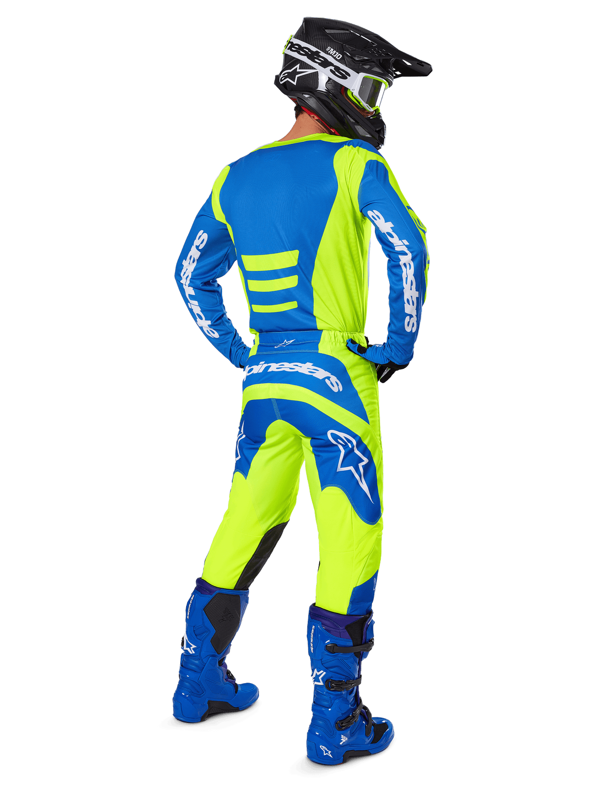 Pilote de motocross vu de dos portant le pantalon Alpinestars Fluid Haul 2025 et le maillot assorti en jaune fluo et bleu, coordonné avec des bottes bleues et un casque Alpinestars noir, équipement de course tout-terrain professionnel