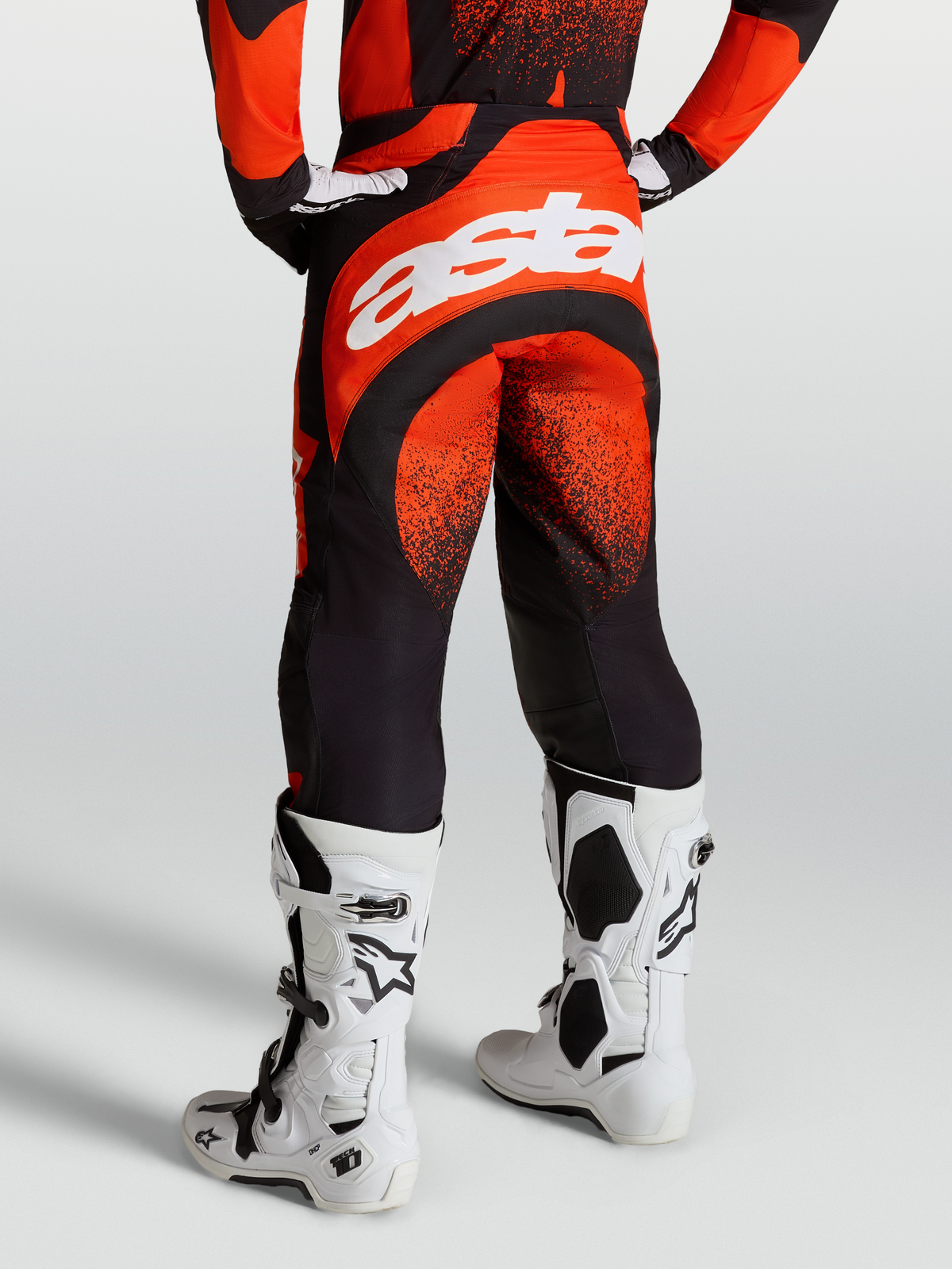Alpinestars Pantalons Techstar Swan, pantalons de motocross homme, rouge cardinal et noir, avec logo Astar blanc à l'arrière et bottes Tech 10 blanches.