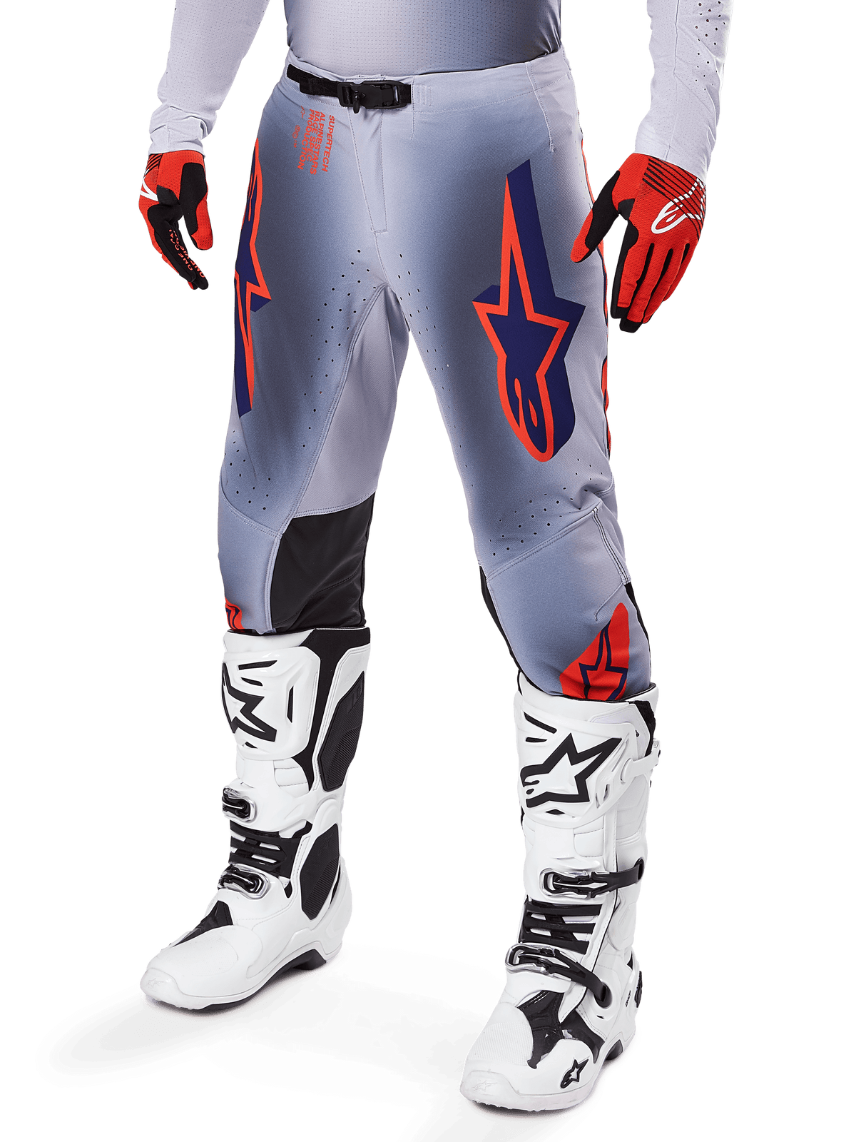 Alpinestars 2025 Supertech Lipan Hose, Motocross-Hose, Grau und Orange Fluo, mit dunkelblauen Sternendesigns und schwarzen Knieinneneinsätzen, getragen mit rot-orangen Handschuhen und weißen Stiefeln, professionelle Offroad-Rennausrüstung