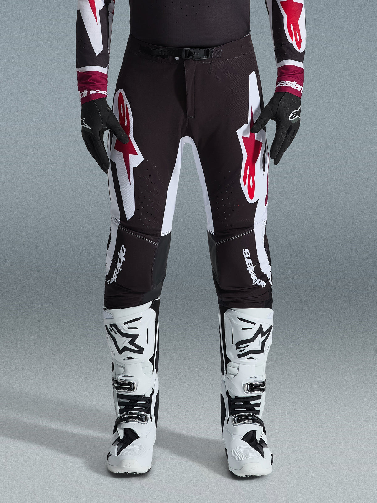 Alpinestars 2026 Supertech AFD Vista Pants, Motocross Pants, Black Red and White, featuring large graphic logos on the thighs and knees, worn with white racing boots and black gloves, athletic race-ready design for elite off-road competition