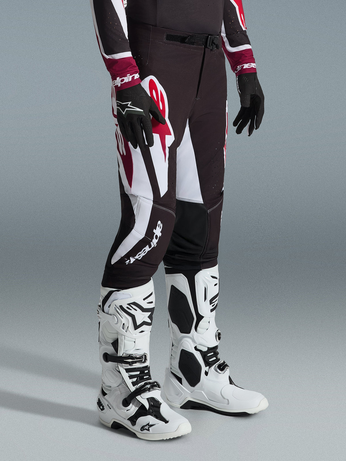 Alpinestars 2026 Supertech AFD Vista Pants, Motocross Pants, Black Red and White, featuring bold graphic patterns and branding, worn with white and black off-road boots and black gloves, professional athletic fit.