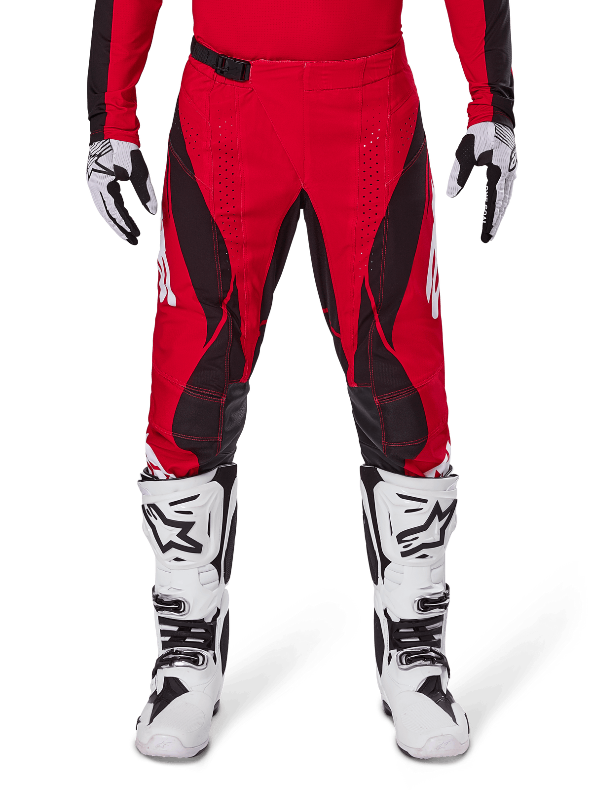 Alpinestars 2025 Techstar Dreem crossbroek, motorcross broek, helderrood en zwart, met hoekige patronen en lasergesneden ventilatiegaten, gedragen met witte motorcrosslaarzen en bijpassende handschoenen voor off-road racing