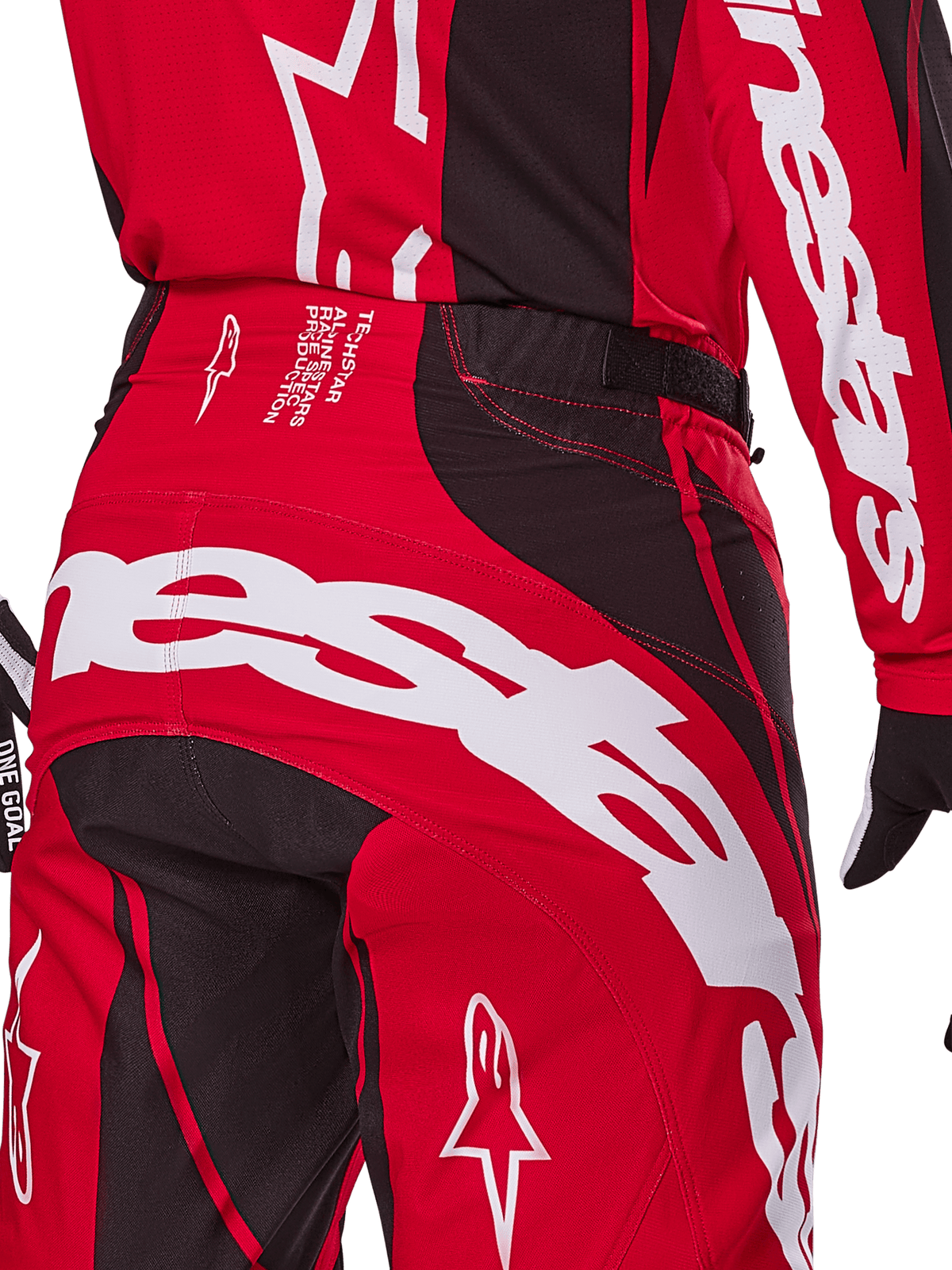 Alpinestars 2025 Techstar Dreem crossbroek, motorcrossbroek, helderrood en zwart, close-up van de achterzijde van de taille en het zitvlak met opvallende witte Alpinestars-branding, zwarte stretchpanelen en technische productietekst op de tailleband, ontworpen voor off-road raceprestaties.