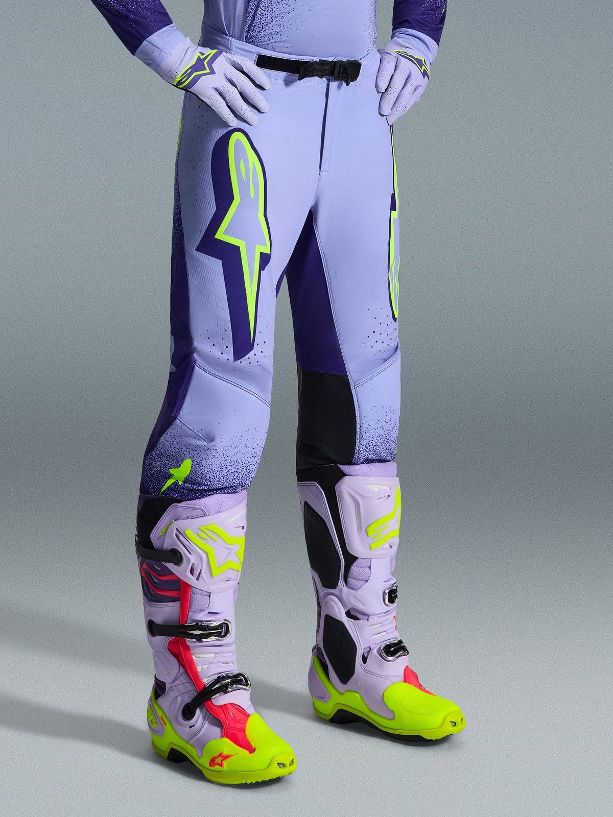 Alpinestars 2026 Supertech Scenz broek, motorcrossbroek, paars en fluogeel, gedragen met bijpassende motorcrosslaarzen en handschoenen, voorzien van grote neongele logo's, atletische pasvorm en lasergesneden perforaties voor ventilatie