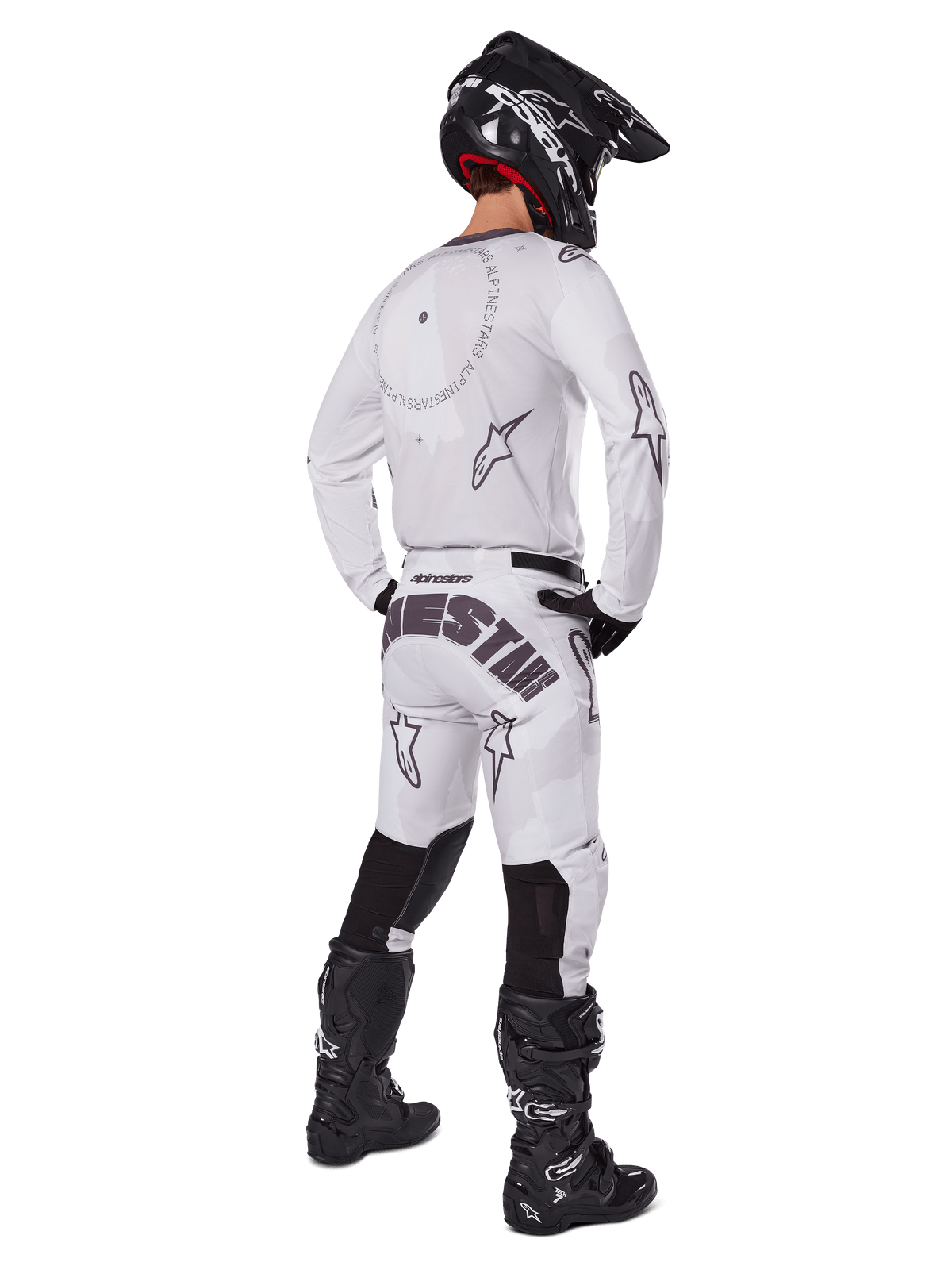 Alpinestars 2025 Racer Hollow Pants, motorcross broek, licht camo bruin en wit, achteraanzicht met opvallende zwarte branding op het zitvlak en sterlogo's, gedragen met bijpassende jersey, zwarte laarzen en een zwarte helm voor een complete off-road racing look