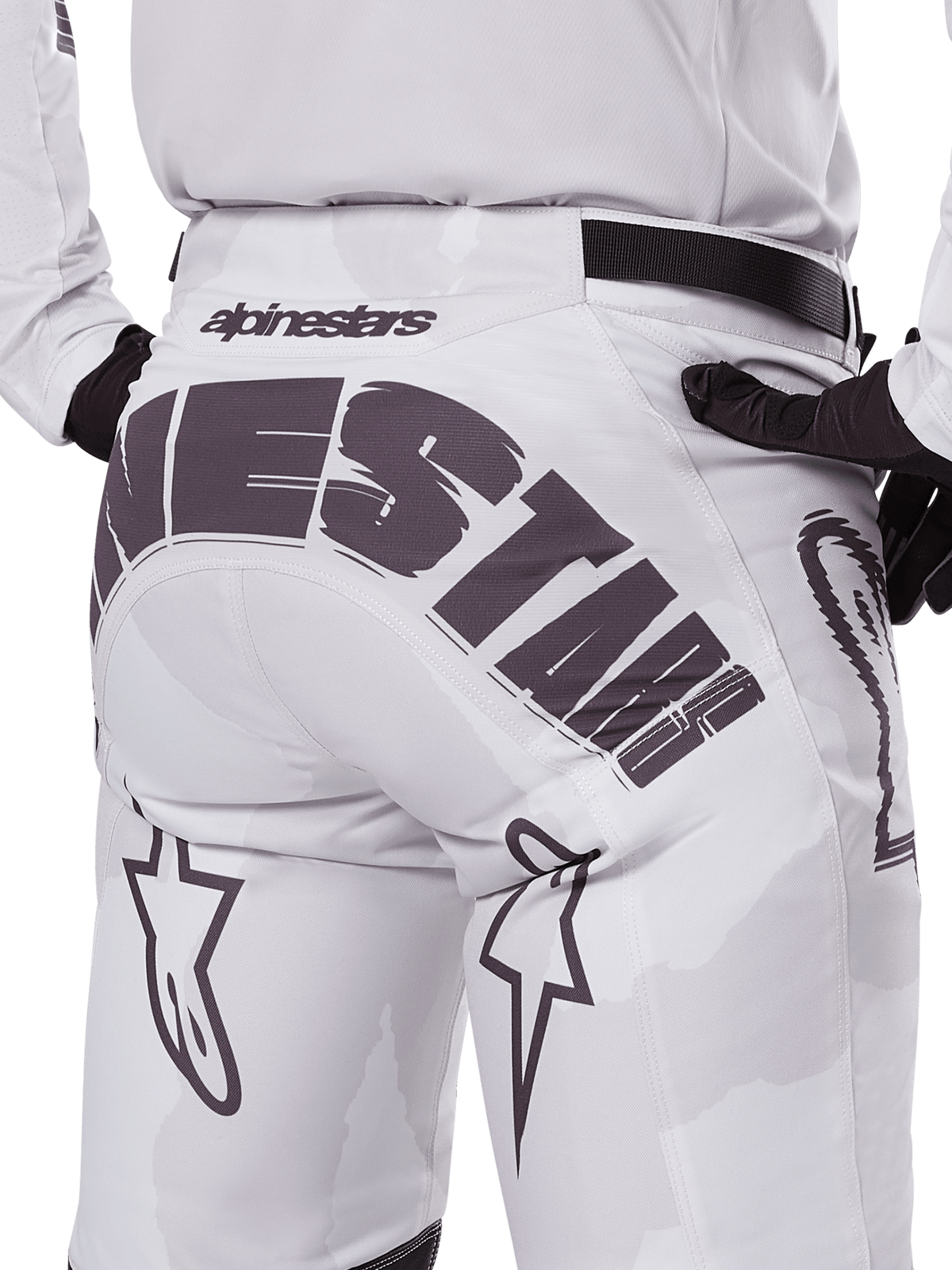 Vue arrière du pantalon Alpinestars Racer Hollow 2025, pantalon de motocross, blanc et camouflage clair, avec marquage Alpinestars noir imposant sur l'assise, porté avec un maillot assorti et des gants noirs