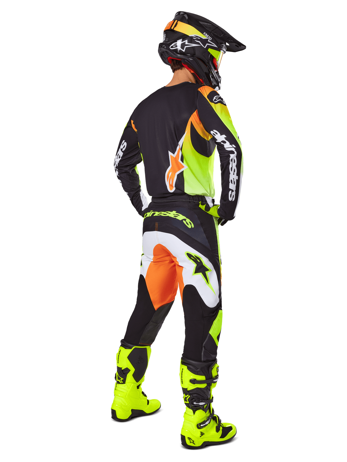 Motocrossrijder van achteren gezien in de Alpinestars 2025 Fluid Wurx Gear Set, zwart shirt met gele en oranje accenten, bijpassende zwarte broek met witte en oranje panelen, felgele laarzen en een zwarte helm, complete off-road race-outfit
