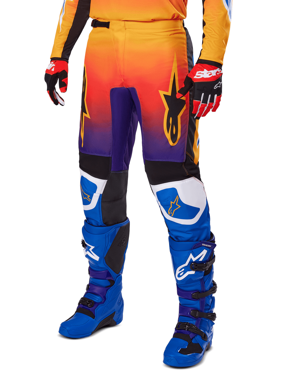 Alpinestars 2025 Fluid Wurx Hose, Motocross-Hose, mehrfarbiger Farbverlauf in Orange, Rot und Lila mit schwarzen und blauen Einsätzen, getragen mit blauen Stiefeln und roten Handschuhen, mit Stern-Logo-Grafiken und weißen Knie-Akzenten, strapazierfähige Performance-Ausrüstung für Offroad-Rennsport