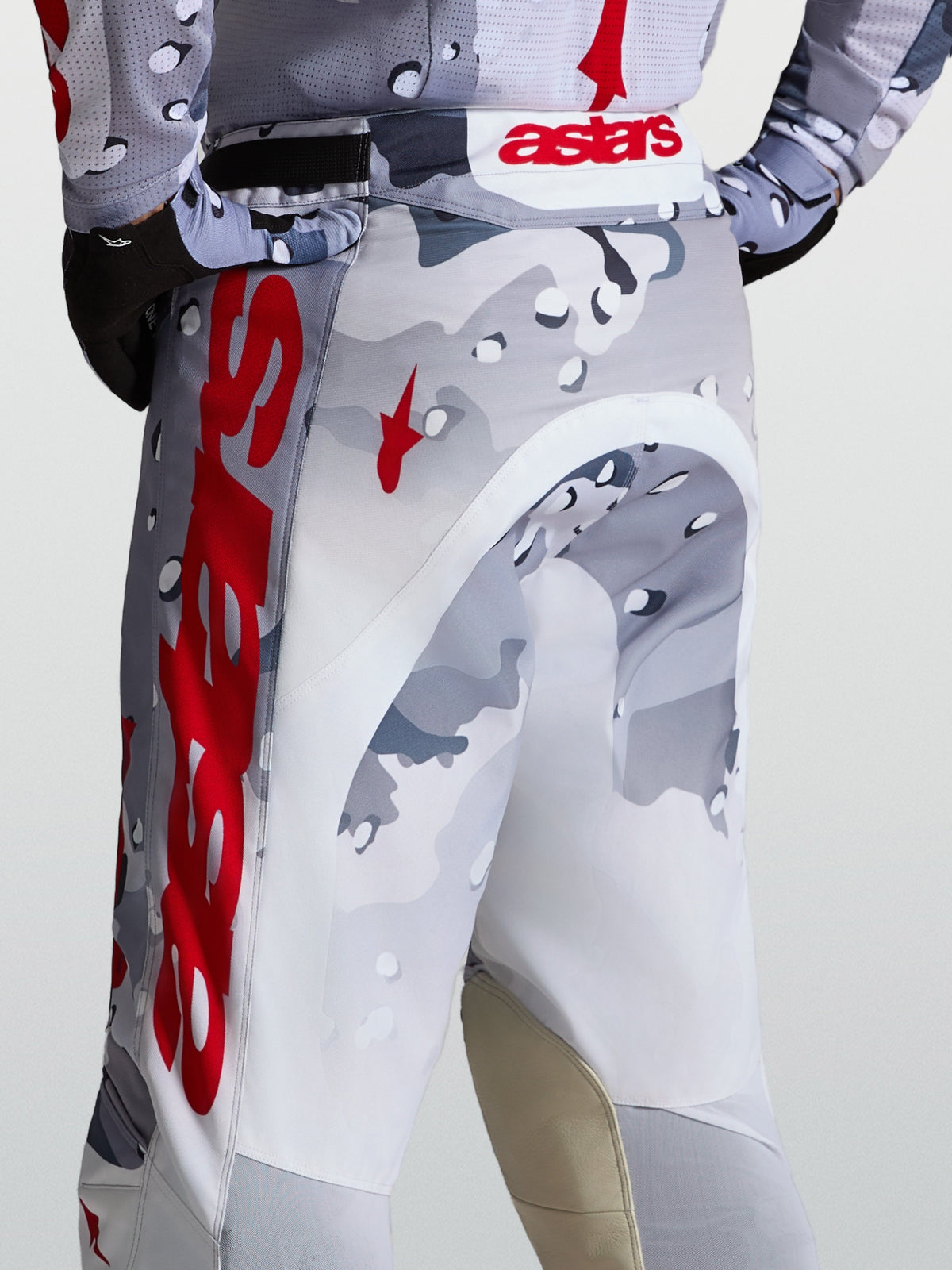 Alpinestars Racer Air Lone motocrossbroek, grijs camouflage en rood, geperforeerd polyweefsel met leren kniestukken.