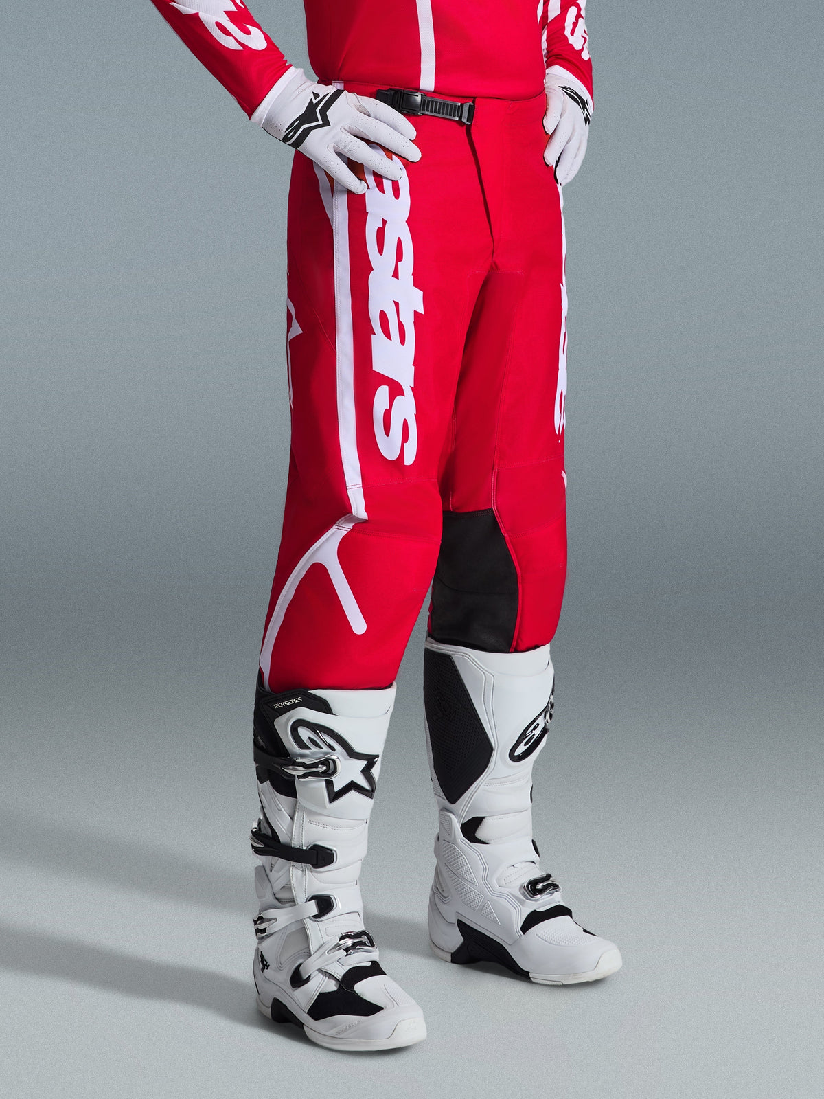 Alpinestars 2026 Fluid Apex Hose, Motocross-Hose, Rot und Weiß, getragen mit weiß-schwarzen Motocross-Stiefeln und Handschuhen, markantes weißes Branding und schwarze Knieinnenseiten, entwickelt für Offroad-Performance