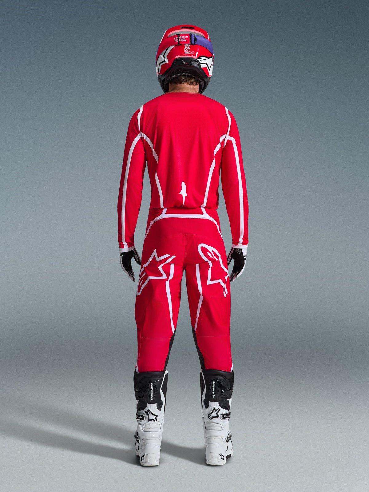 Alpinestars 2026 Fluid Apex Hose, Motocross-Hose, Rot und Weiß, Rückansicht getragen mit passendem Trikot, rotem Helm und weiß-schwarzen Stiefeln, mit großen weißen Astar-Logos auf den Beinen, abgestimmtes Outfit für den Offroad-Rennsport