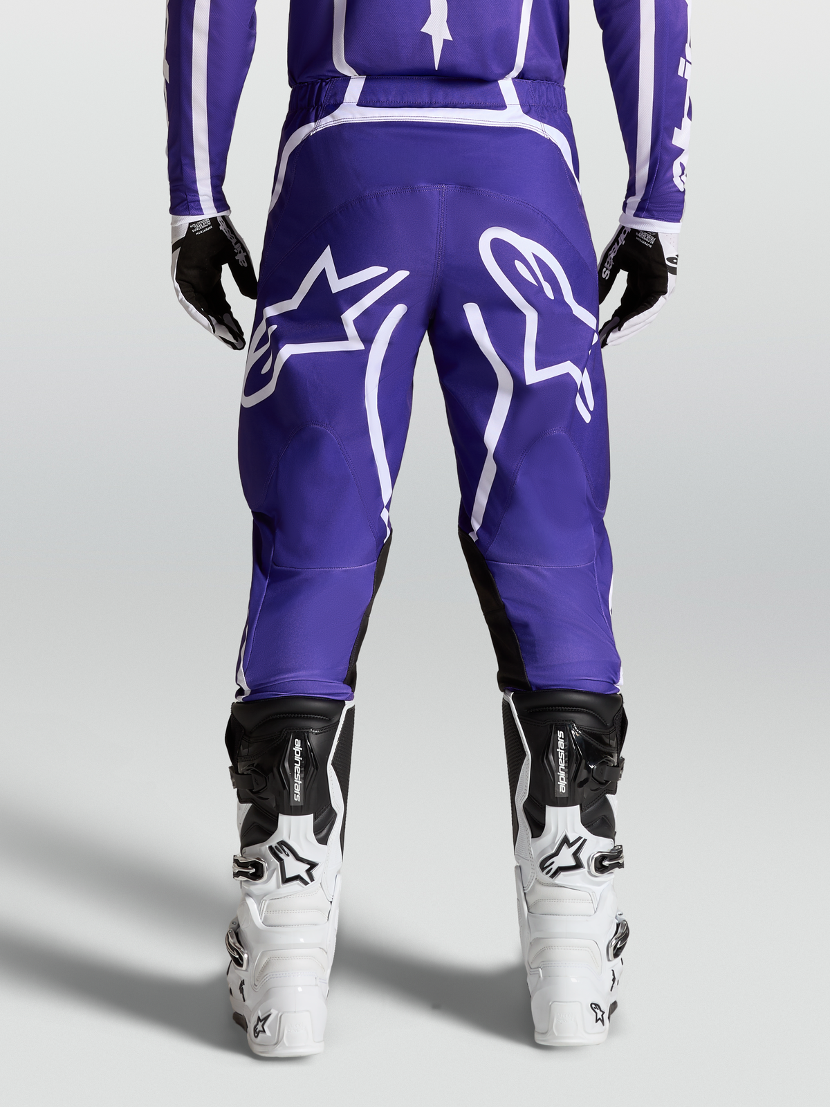 Alpinestars Pantalon Fluid Apex V2, pantalon de motocross tout-terrain, bleu et blanc, vue de dos sur mannequin avec bottes blanches, poly-tissu 600D durable et design ergonomique.