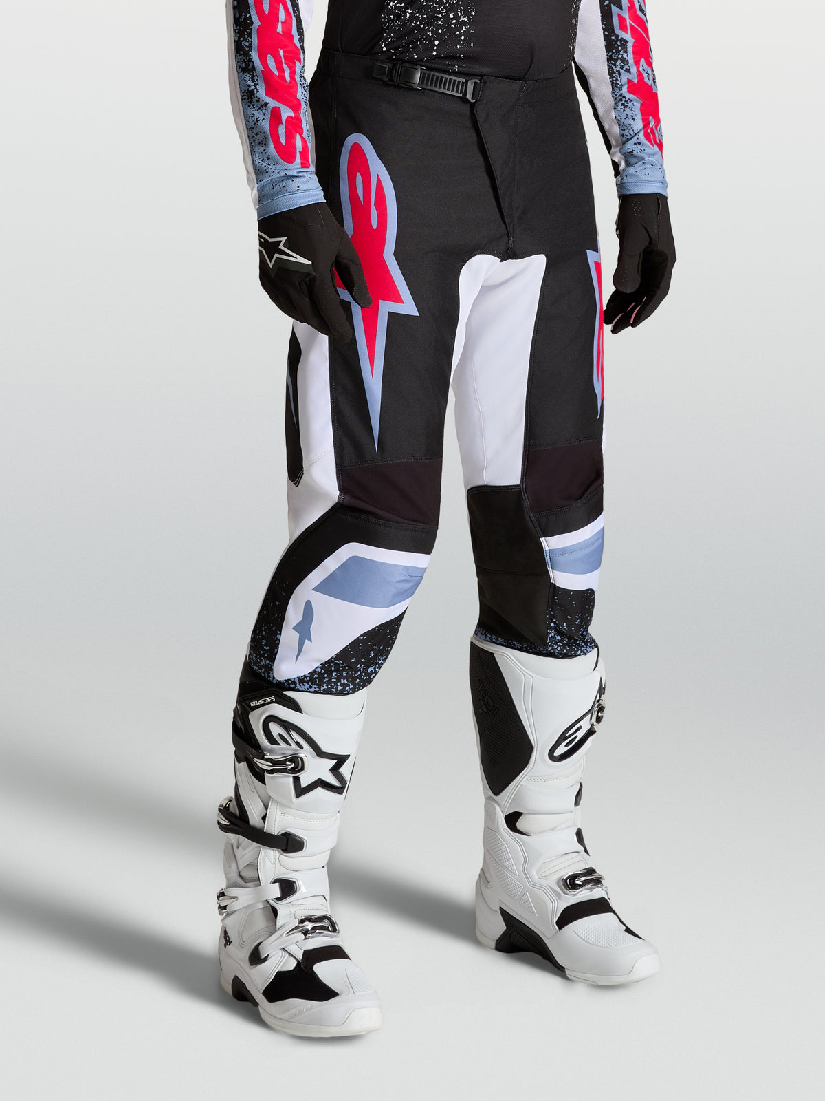 Alpinestars Fluid Drag broek, heren-motocrossbroek in zwart en wit met fluo rode en lichtblauwe accenten, ergonomische pasvorm voor off-road racing.