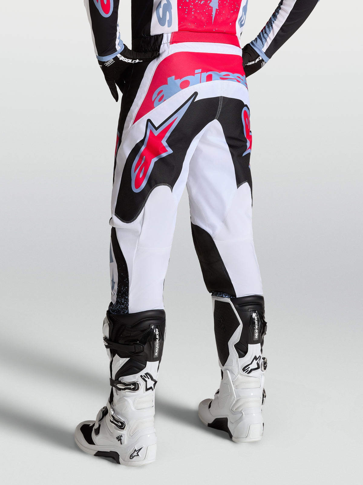 Alpinestars Fluid Drag broek, heren performance motocrossbroek in wit en zwart met rode en lichtblauwe accenten, achteraanzicht.