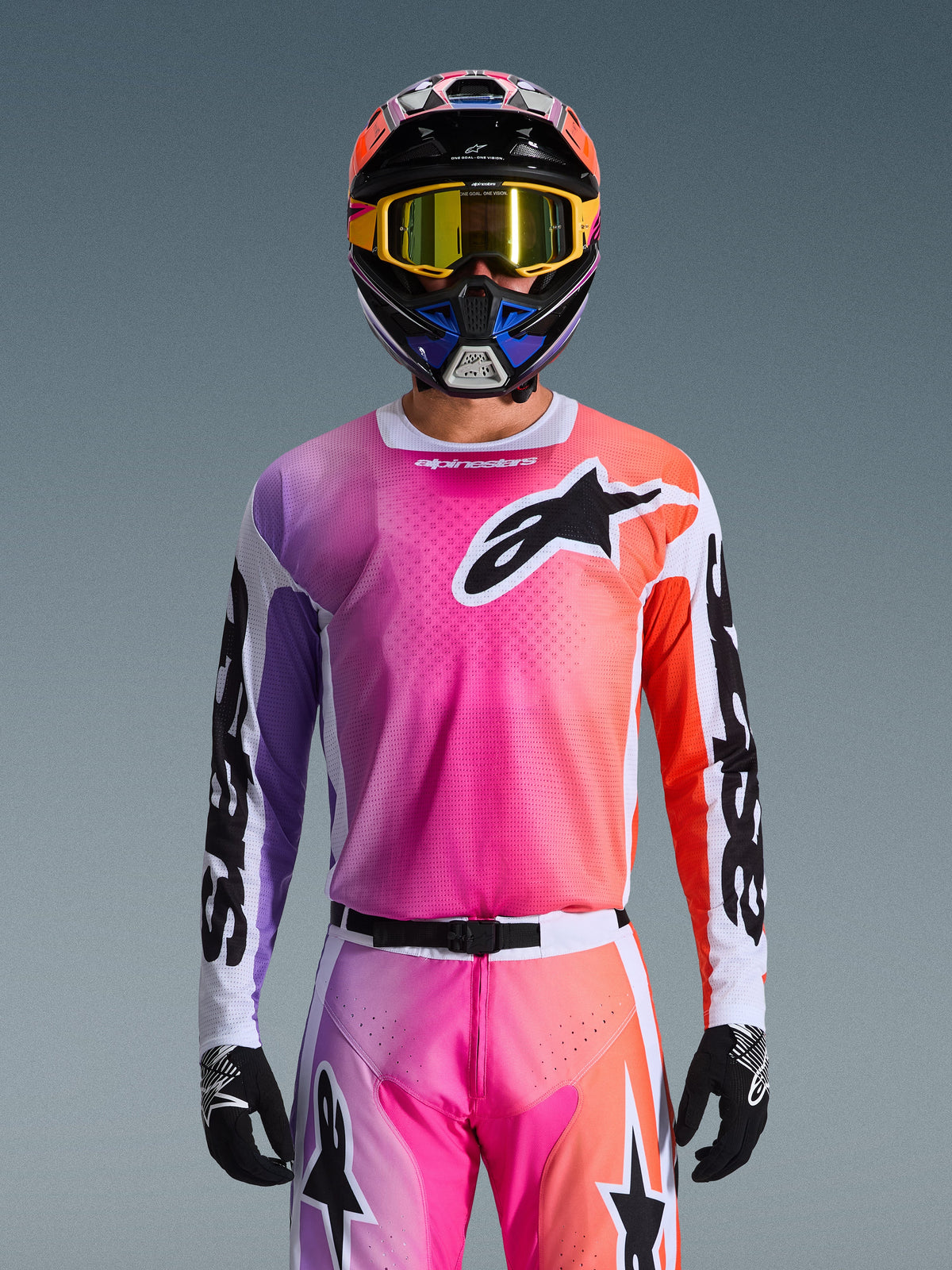 Maillot Alpinestars Racer Air Portl 2026, maillot de motocross, dégradé rose, violet et orange éclatant, porté avec un casque et des lunettes assortis, avec un grand logo d'étoile noire sur la poitrine, construction en maille respirante, équipement de performance pour la course tout-terrain