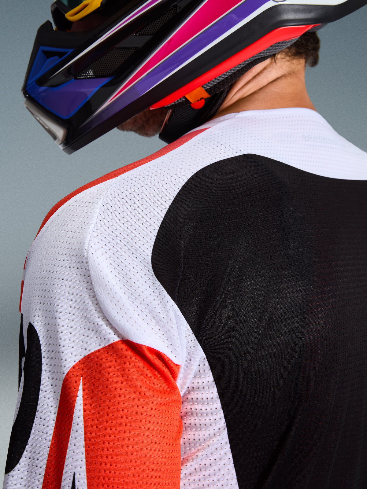 Alpinestars 2026 Racer Air Portl Jersey, maillot de motocross, multicolore avec panneaux blancs, noirs et rouges, gros plan sur la maille perforée au niveau de l'épaule et du dos pour la ventilation, porté avec un casque de motocross coloré