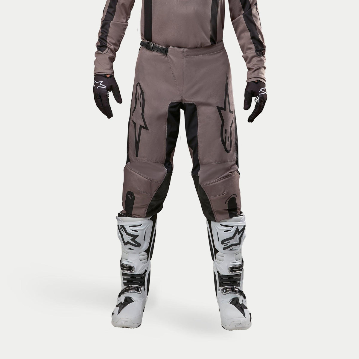 Alpinestars 2024 Fluid Lurv Hose, Motocross-Hose, Mud Black, getragen mit passendem Jersey, schwarzen Handschuhen und weißen Stiefeln, mit großen schwarzen Logos auf den Oberschenkeln, ergonomischer Passform und strapazierfähigem Material für Offroad-Rennen