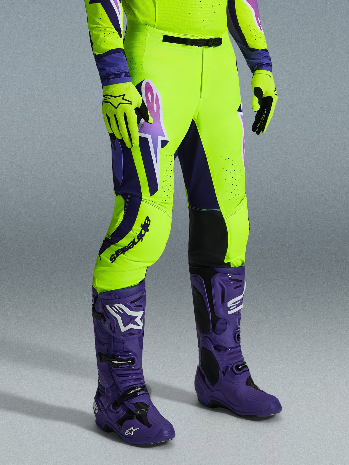 Alpinestars 2026 Supertech Vista Pants, Motocross Pants, Bright Neon Yellow, Purple and Black, worn with matching purple boots and yellow gloves, featuring bold branding on the thigh and a performance athletic fit.