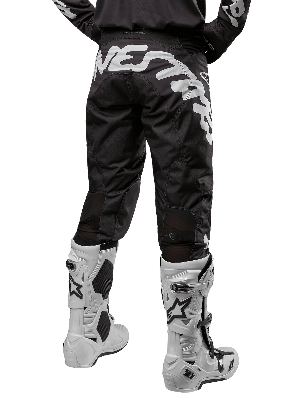 Alpinestars 2024 Racer Hana Hose, Motocross-Hose, Schwarz und Weiß, Rückansicht mit markanten weißen Grafiken auf der Rückseite, strapazierfähiges Material, kombiniert mit weißen Motocross-Stiefeln, Hochleistungs-Sportbekleidung für Offroad-Einsätze.