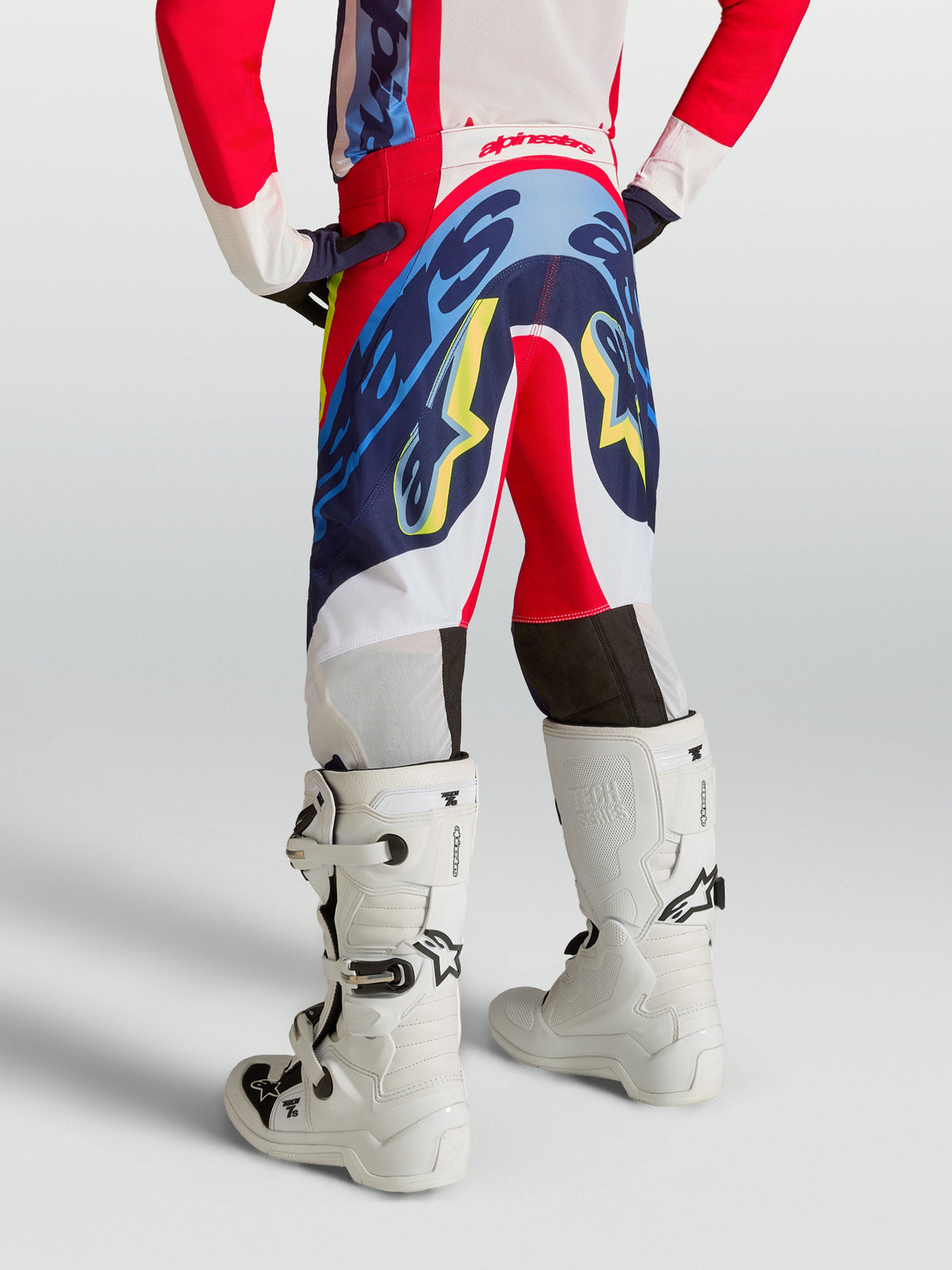 Pantalon Supertech Dyna Junior Alpinestars, pantalon de motocross rouge et bleu marine, vue de dos pour jeune pilote.