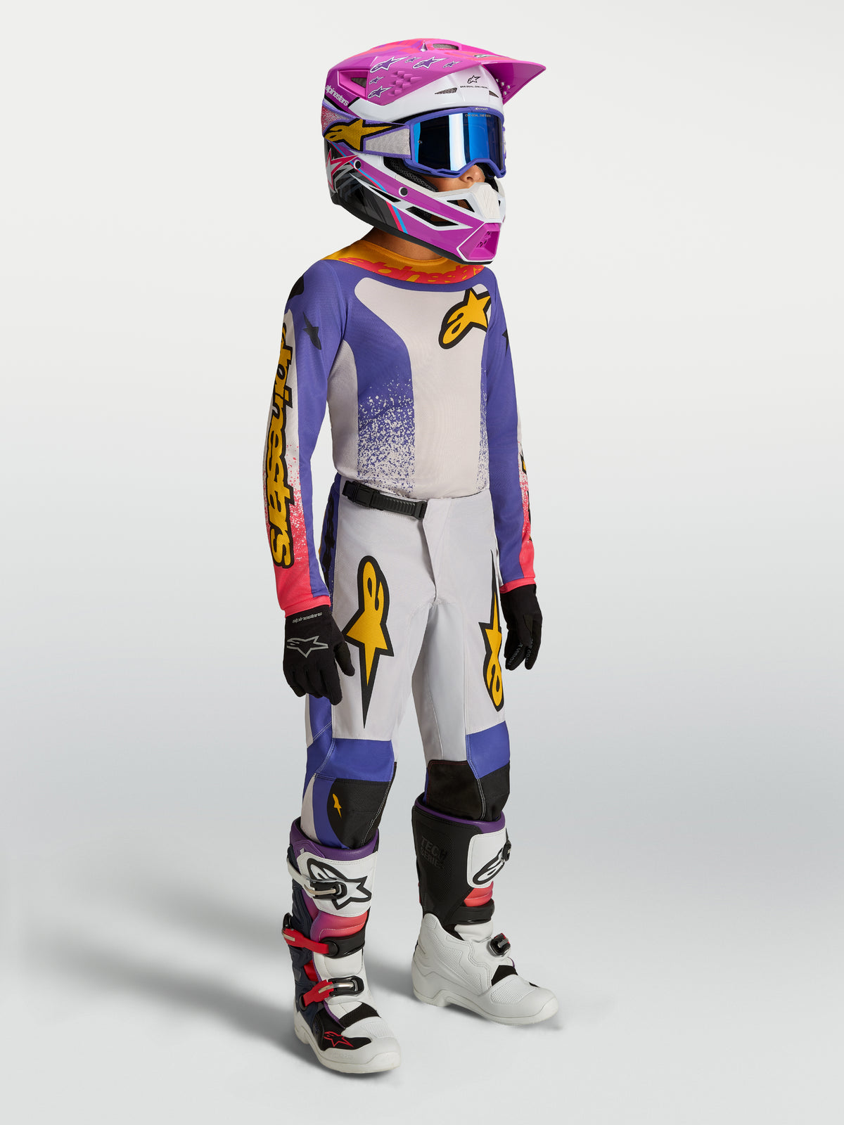Alpinestars Jeugd Fluid Drag broek, blauwe en gouden motocrossbroek voor jeugd, ergonomische pasvorm, gedragen door model.