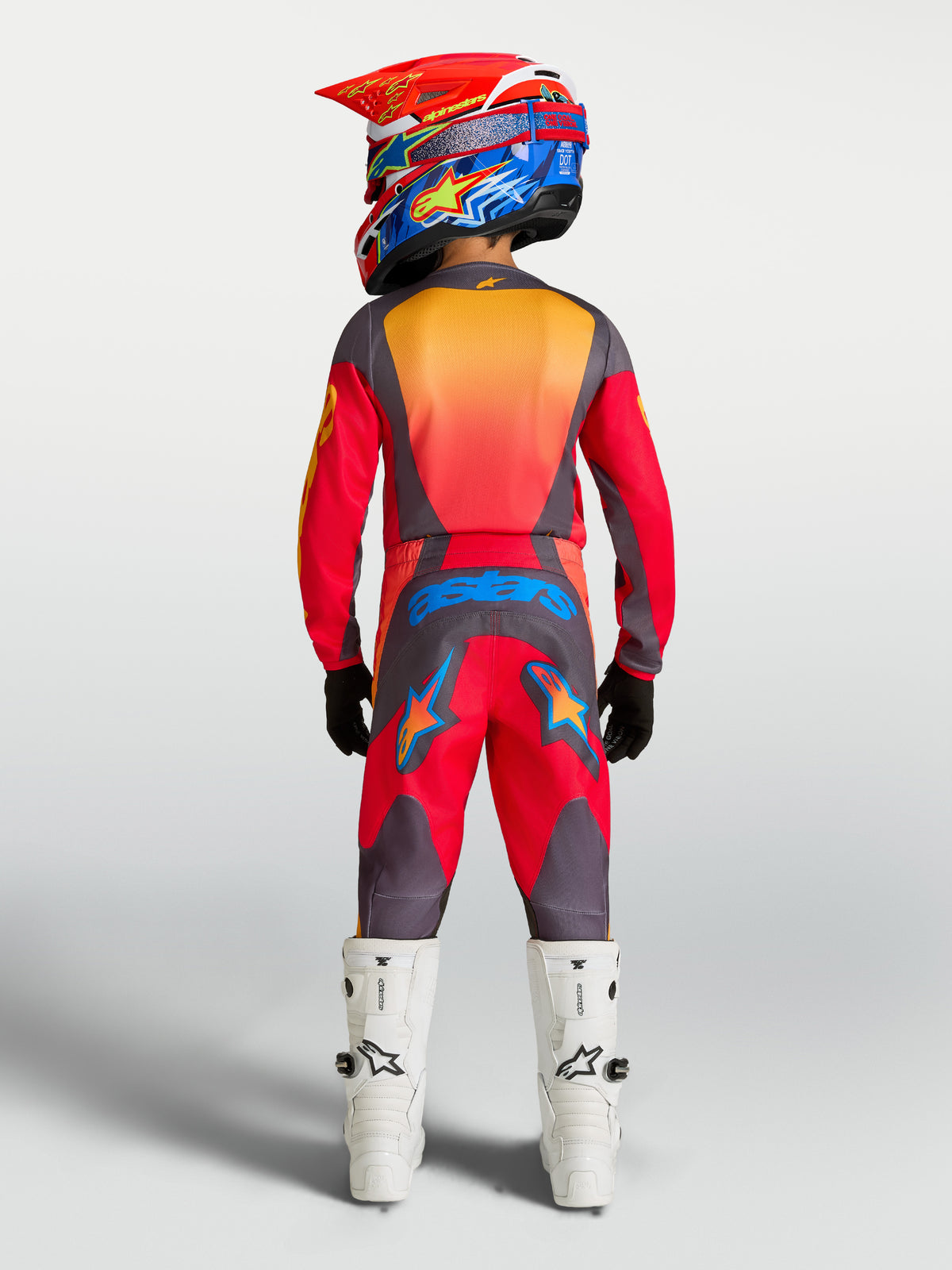 Alpinestars Youth Fluid Hunt Pants, Red and Gray Motocross Pants, rear view of youth rider in full gear with white boots.