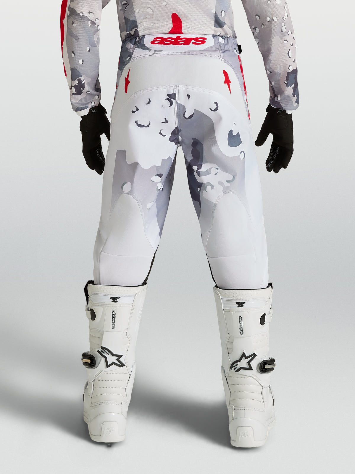Pantalon Fluid Lone Junior Alpinestars, pantalon de motocross gris camo et blanc, accents rouges, vue de dos sur pilote