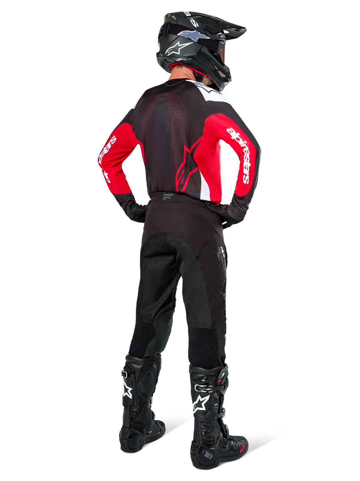 Motocross-Fahrer in der Rückansicht, Alpinestars Pro-Dura Jersey in Schwarz, Hellrot und Weiß, kombiniert mit schwarzer Motocross-Hose, Helm und Stiefeln, zeigt das Rückendesign und die Ärmellogos, abgestimmte Offroad-Rennausrüstung.