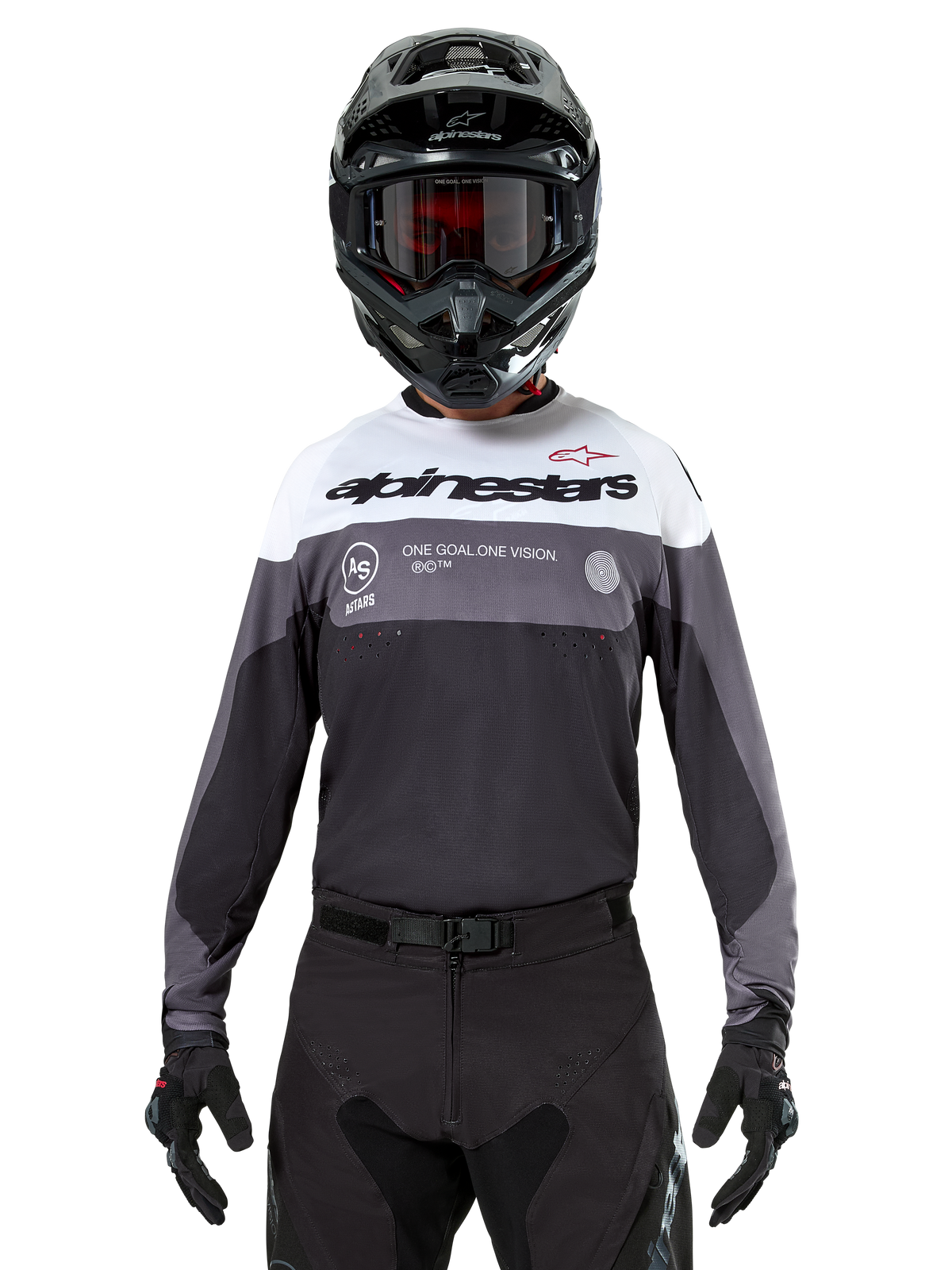 Pilote de motocross portant le maillot Alpinestars Pro-Dura en Black Magnet White, haut de performance à manches longues avec blocs de couleurs blancs et gris, porté avec un casque et des lunettes noirs, arborant le marquage « alpinestars » et le slogan « ONE GOAL ONE VISION », équipement de course de moto tout-terrain