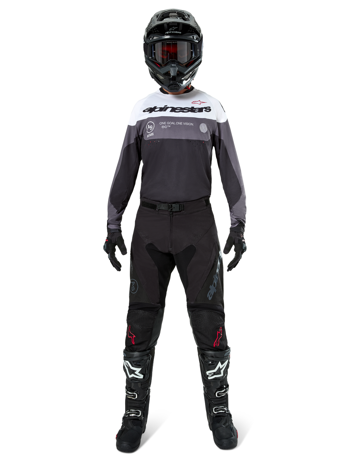 Pilote de motocross portant une tenue de course complète, maillot Pro-Dura en Black Magnet White avec haut de la poitrine blanc et détails gris, associé à un pantalon noir, un casque noir avec lunettes sombres, des bottes noires et blanches, et des gants noirs, ensemble coordonné pour l'enduro et le tout-terrain