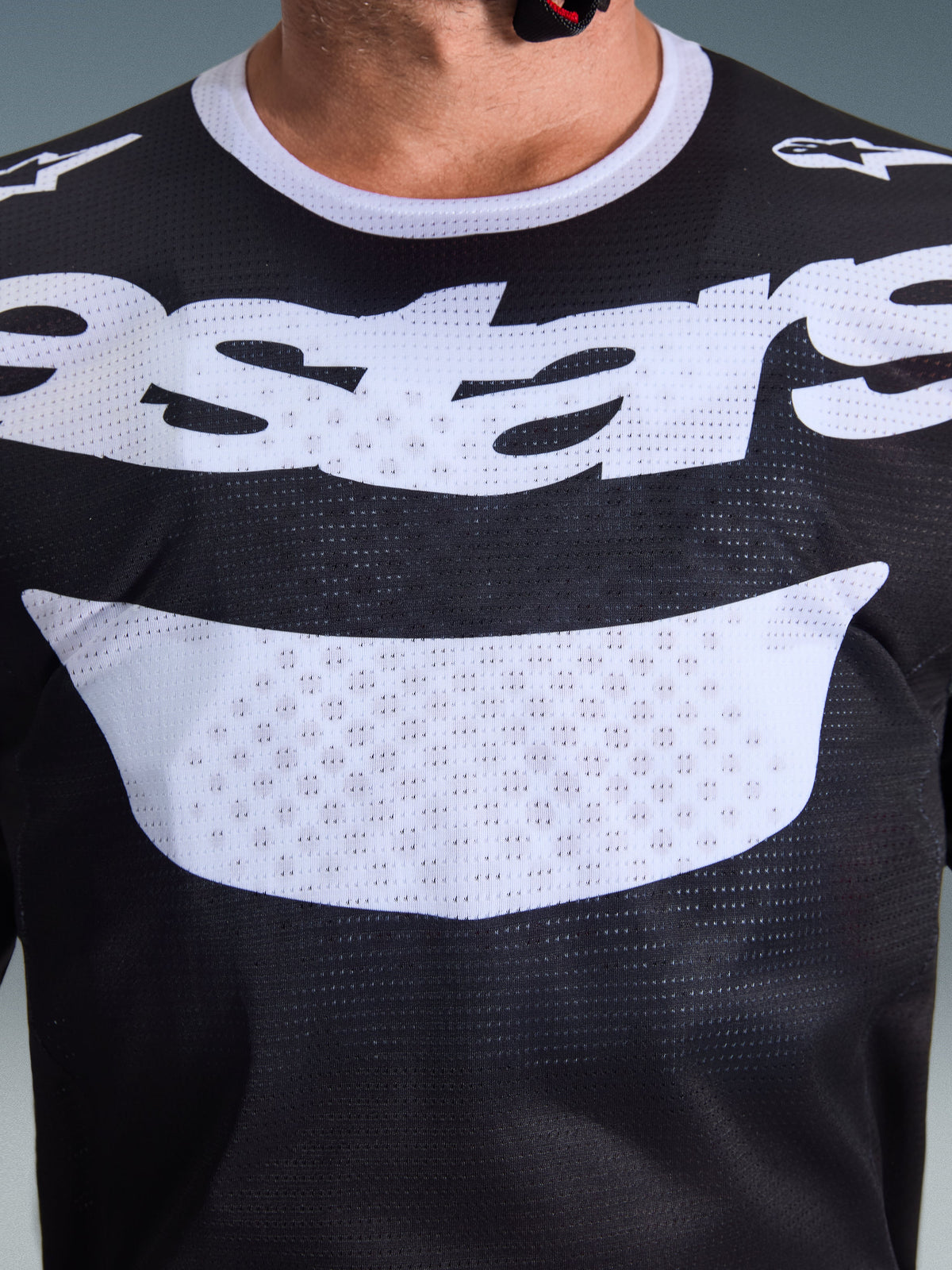 Maillot Alpinestars Racer Air Riway 2026, maillot de motocross, noir et blanc, vue rapprochée de la poitrine avec un grand logo blanc, texture détaillée du tissu en maille aérée, équipement technique respirant pour la conduite tout-terrain