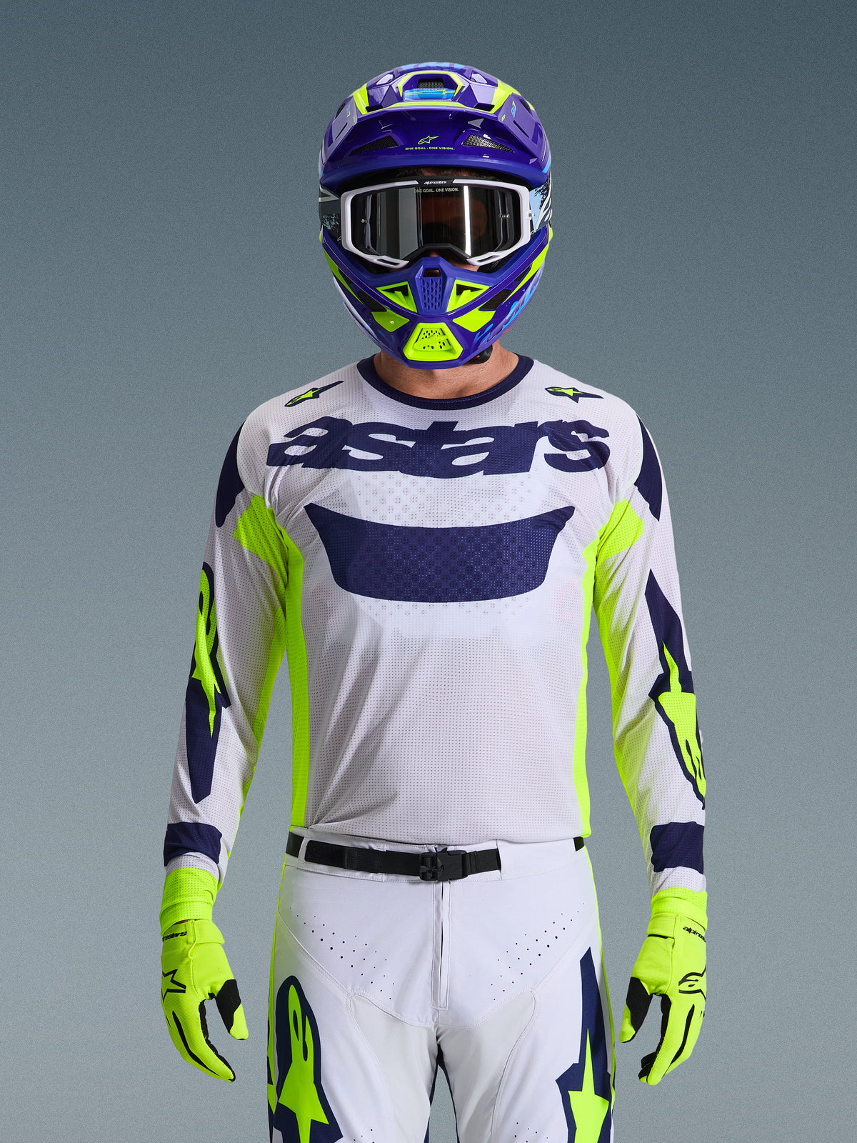 Alpinestars 2026 Racer Air Riway Ausrüstungsset, Motocross-Fahrer, weißes Mesh-Trikot mit navyblauem „astars“-Branding und neongelben Akzenten, passende weiße Hose mit navyblauen und neongelben Grafiken, neongelbe Handschuhe, lila und neongelber Helm mit weißer Brille, Studioaufnahme einer kompletten Offroad-Rennausrüstung