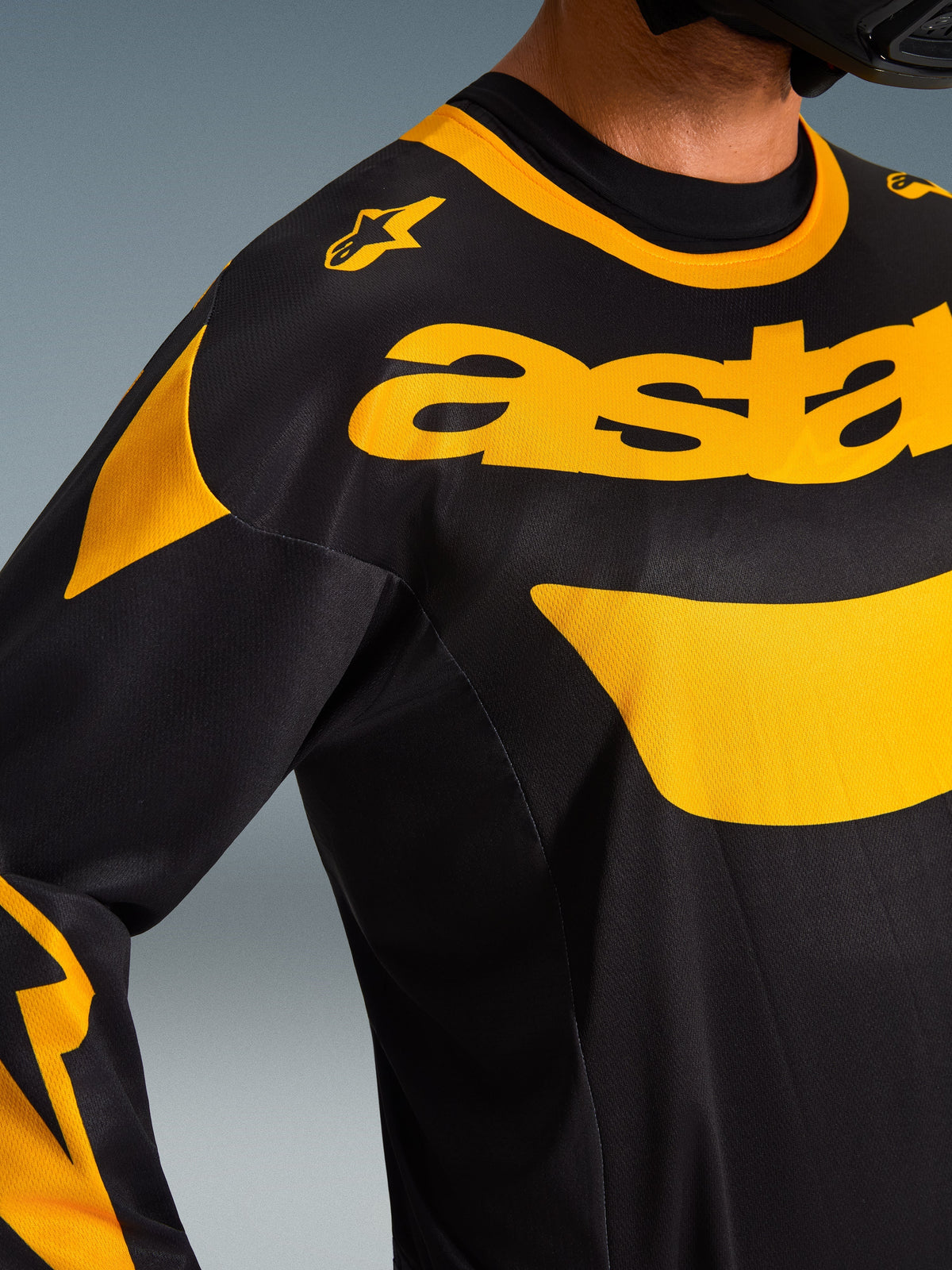 Alpinestars 2026 Racer Riway Jersey, motocross jersey, geel en zwart, close-up van de borst en schouder, met opvallende gele 'astars' branding en grafische accenten op zwart polyfabric, hoogwaardige off-road kleding