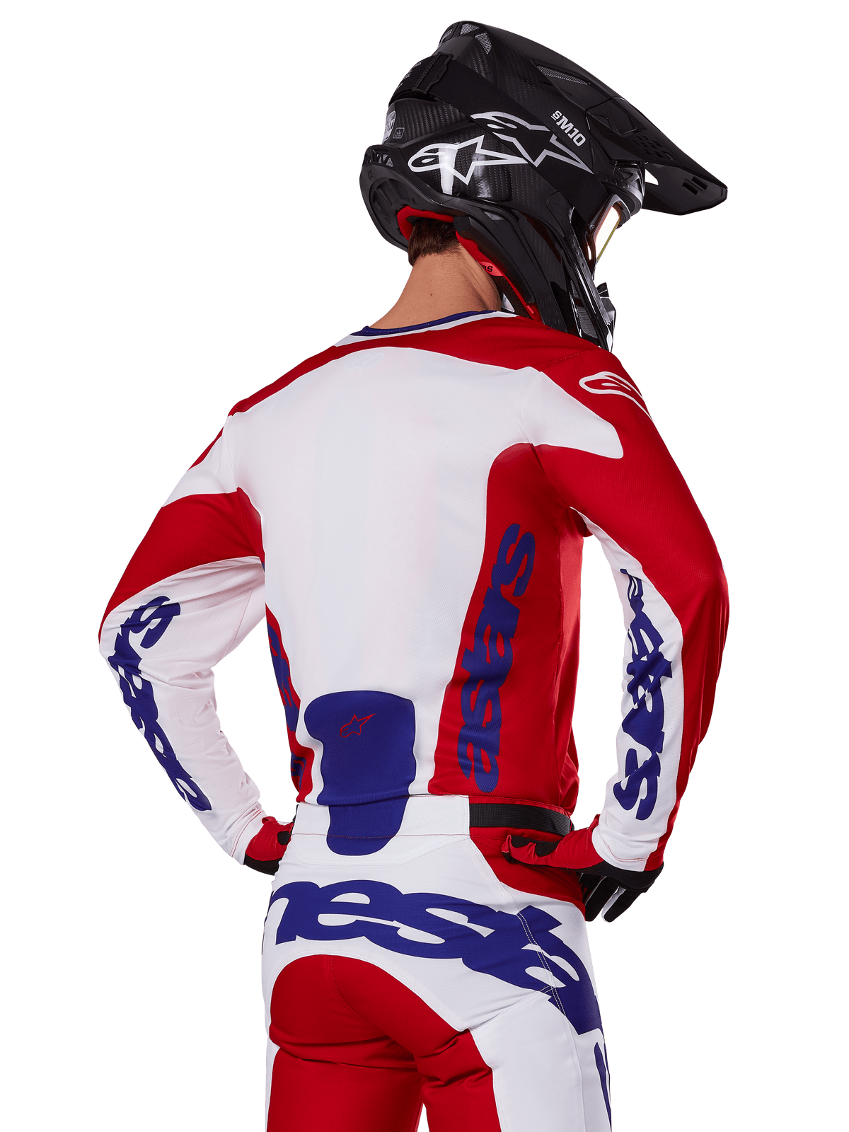 Alpinestars 2025 Racer Veil Trikot und Hose, Motocross-Ausrüstungsset, Hellrot, Weiß und Blau, Rückansicht eines Fahrers in passender Ausrüstung und schwarzem Motocross-Helm, mit markantem blauem Alpinestars-Branding, technische Offroad-Rennbekleidung