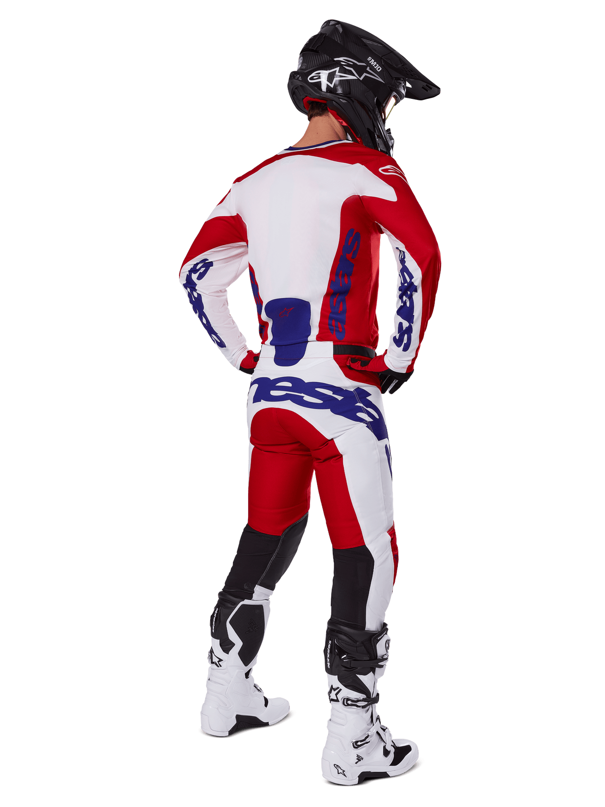 Motocross-Fahrer in der Rückansicht, trägt das Alpinestars 2025 Racer Veil Trikot und die Hose in Rot und Weiß, mit blauem Branding, schwarzem Helm und weißen Stiefeln, komplettes Ausrüstungsset für Offroad-Rennen