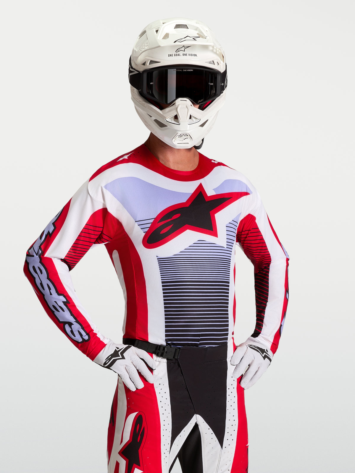 Maillot Alpinestars Techstar Maven, maillot de motocross pour homme, rouge et blanc, coupe athlétique de course, logo étoile Astars noir, porté avec un casque et des gants blancs, équipement tout-terrain performant